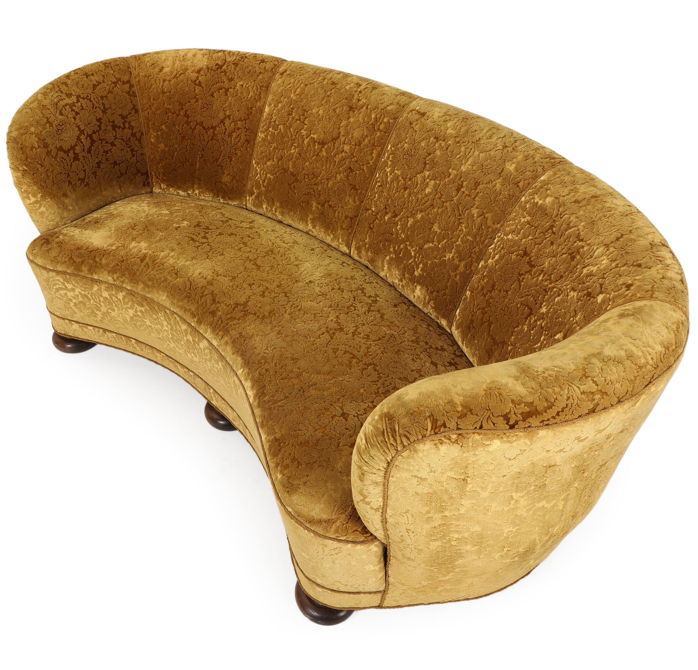 Large banana shaped or curved sofa made in Denmark, circa 1940. This sofa will make strong statement in any room. Beautiful round voluptuous lines and with large bun feet providing a for an elegant and impressive look with it's long length. It has a