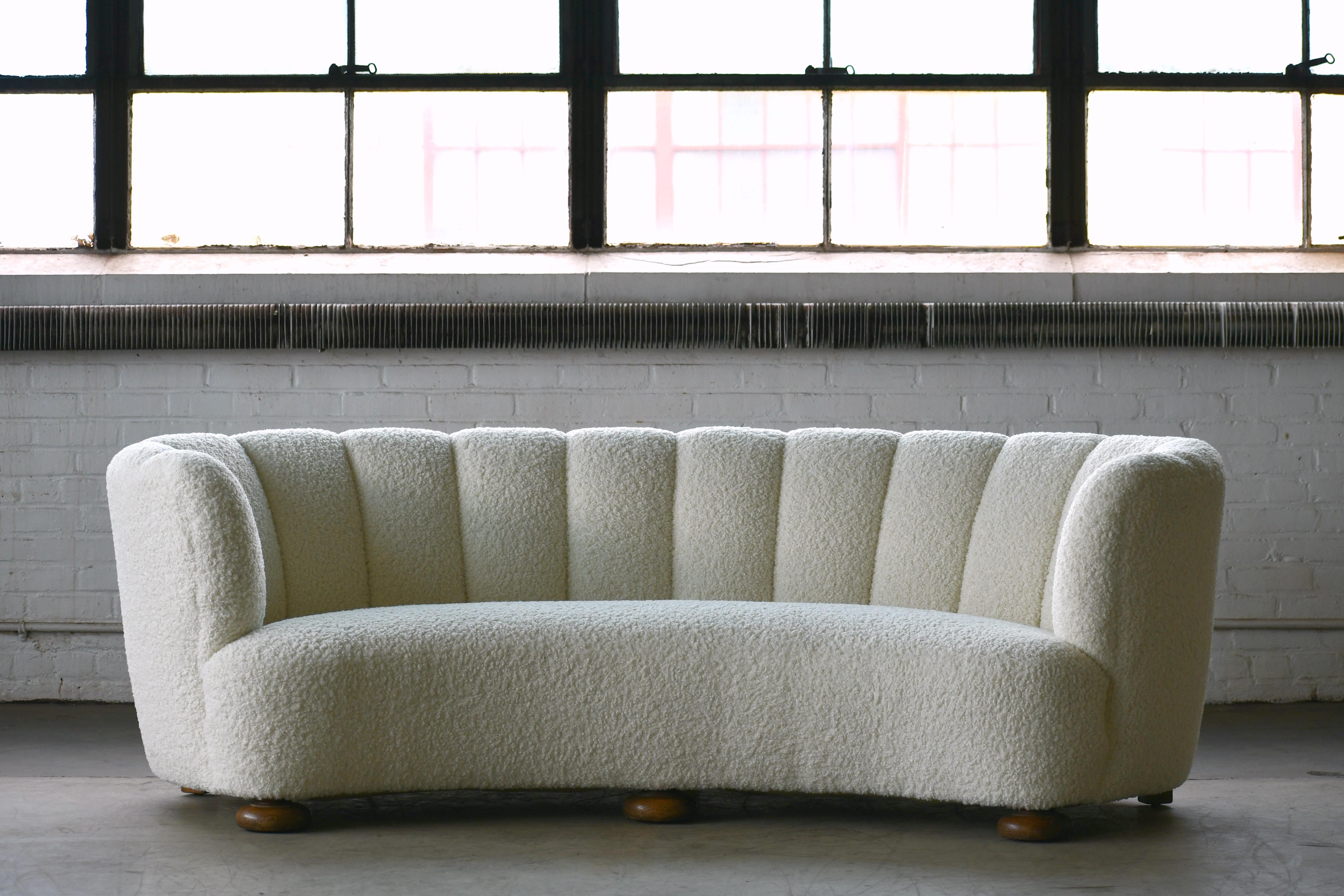 Viggo Boesen style banana shaped or curved sofa made in Denmark, circa 1940. This sofa will make strong statement in any room. Beautiful round voluptuous lines and with large block legs. Fully refurbished and newly upholstered a soft elegant bouclé