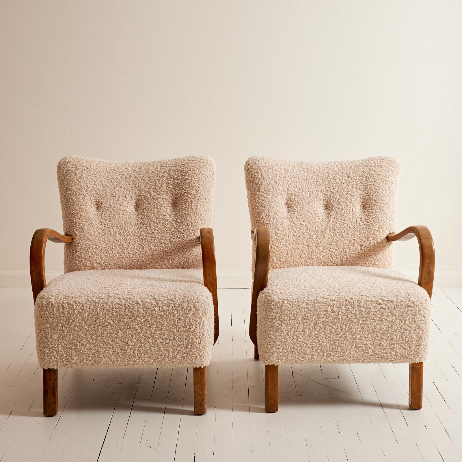 These 1940's Danish lounge chairs with curved beech arm rests have been reupholstered with a curly boucle fabric that is similar to the look of sheepskin. The fabric adds a subtle texture to any room. The easy shape of these chairs are extremely