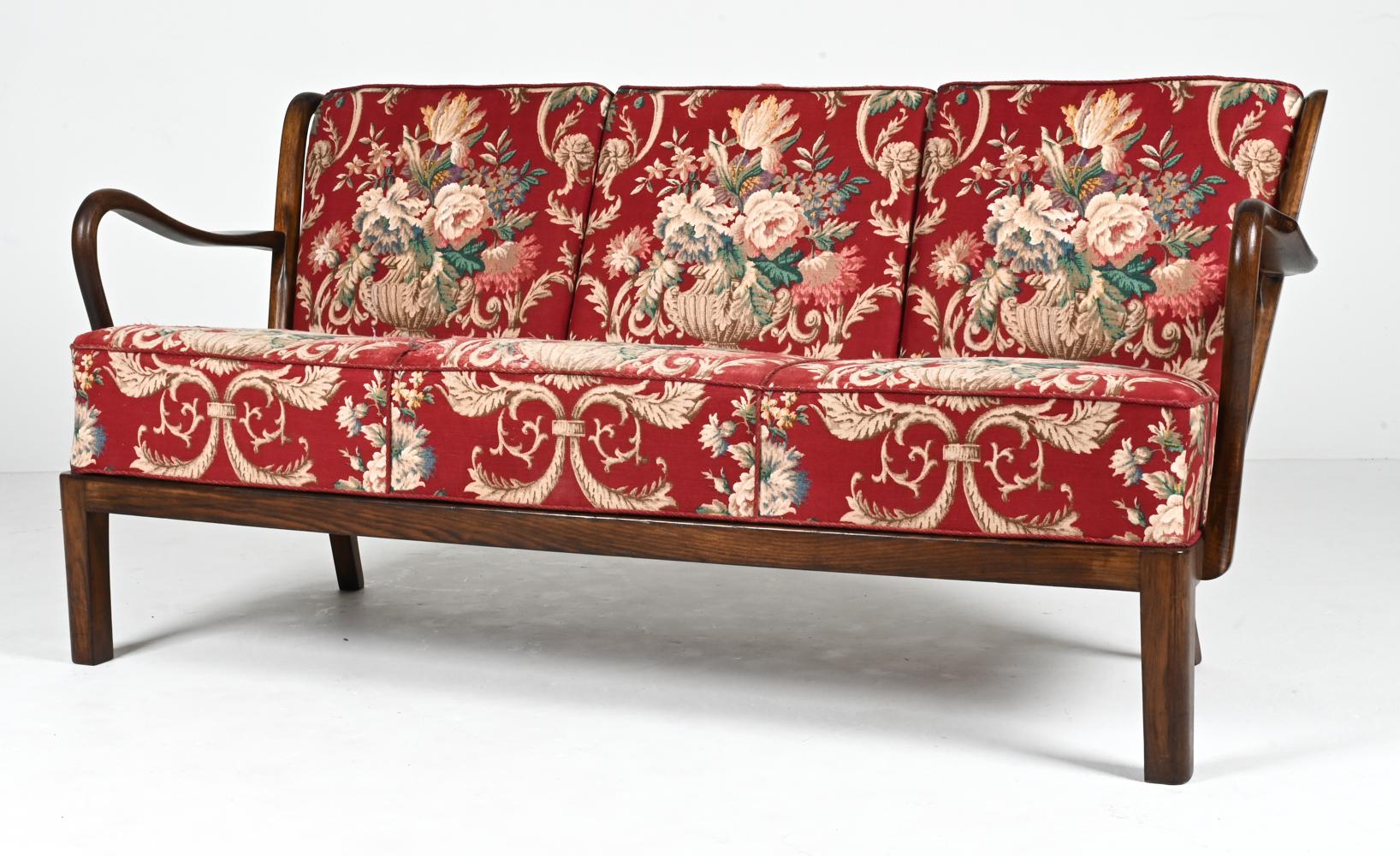 Step into the enchanting world of Danish craftsmanship with this exquisite Danish 1940s Open Arms Sofa, a masterpiece in carved beech wood designed by the skilled artisan Alfred Christensen. With its captivating blend of timeless design and