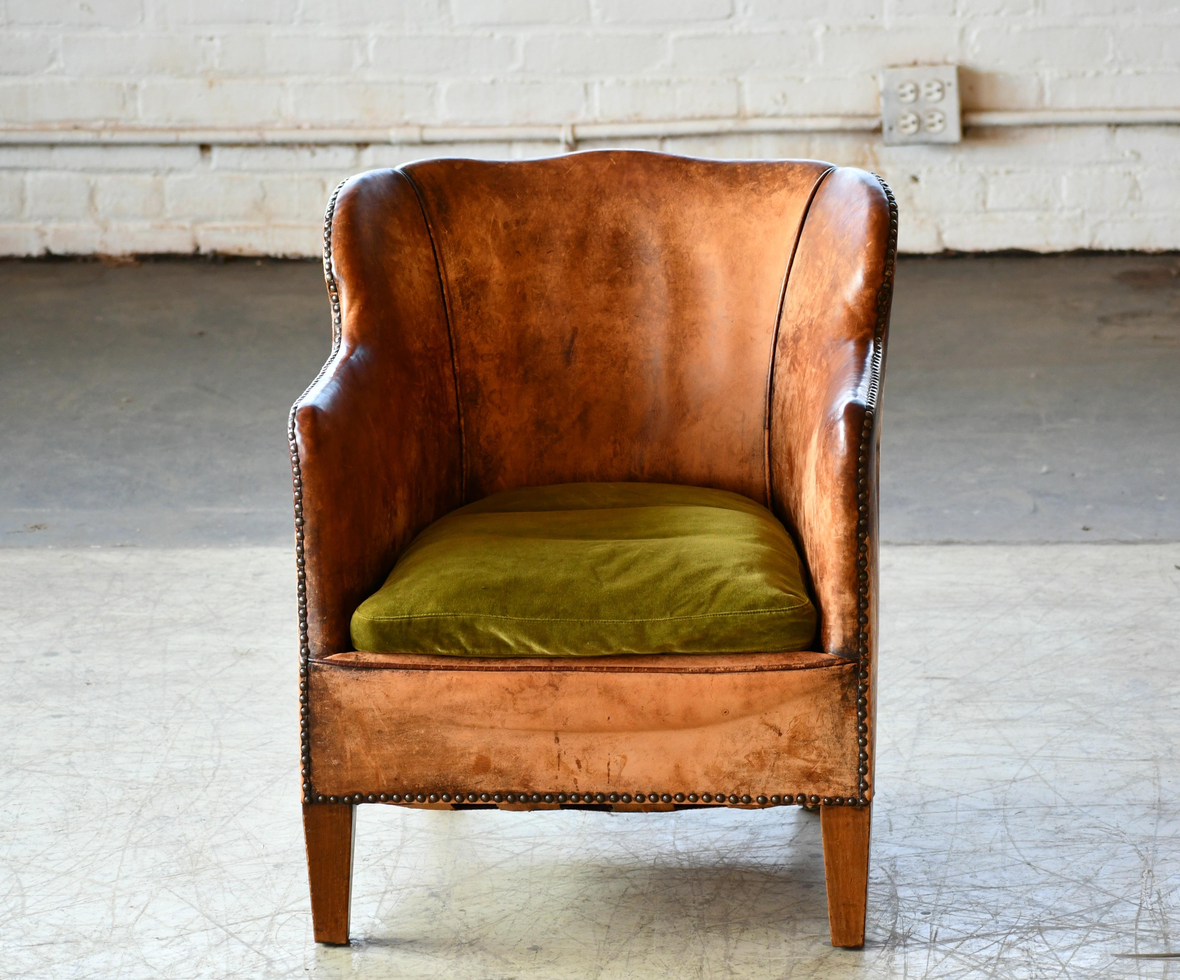 Charming small scale Danish club chair made by Danish Furniture Maker Oskar Hansen around the mid-1930s. Covered in original cognac brown leather with a smooth back. Overall good condition for its age and use with lots noble patina and wear
