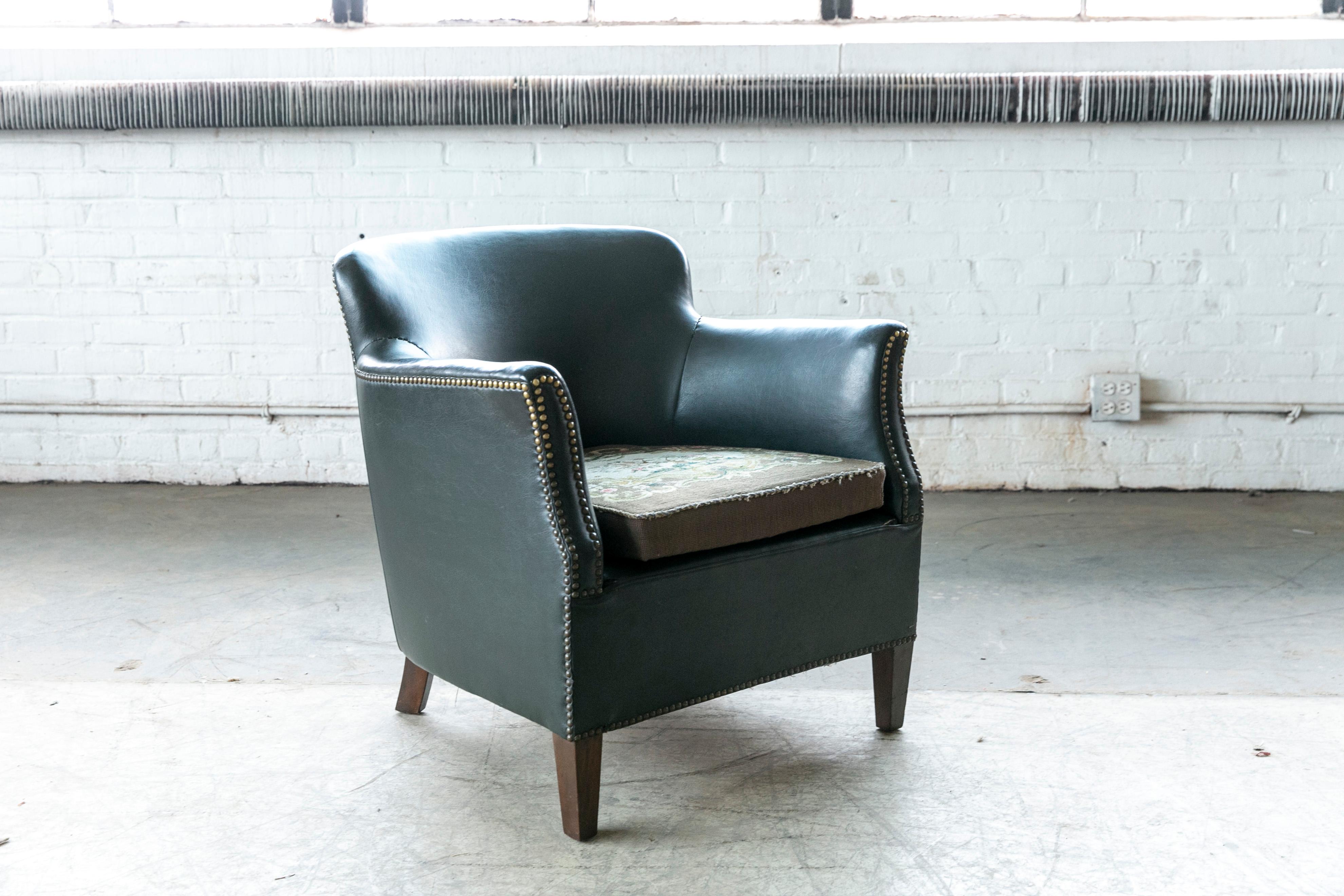 Charming small scale Danish club chair likely made by Danish Furniture Maker Oskar Hansen around the mid-1930s to early 1940's. Covered in dark green leather with a smooth back and brass tacks for decoration. It has been reupholstered at a later
