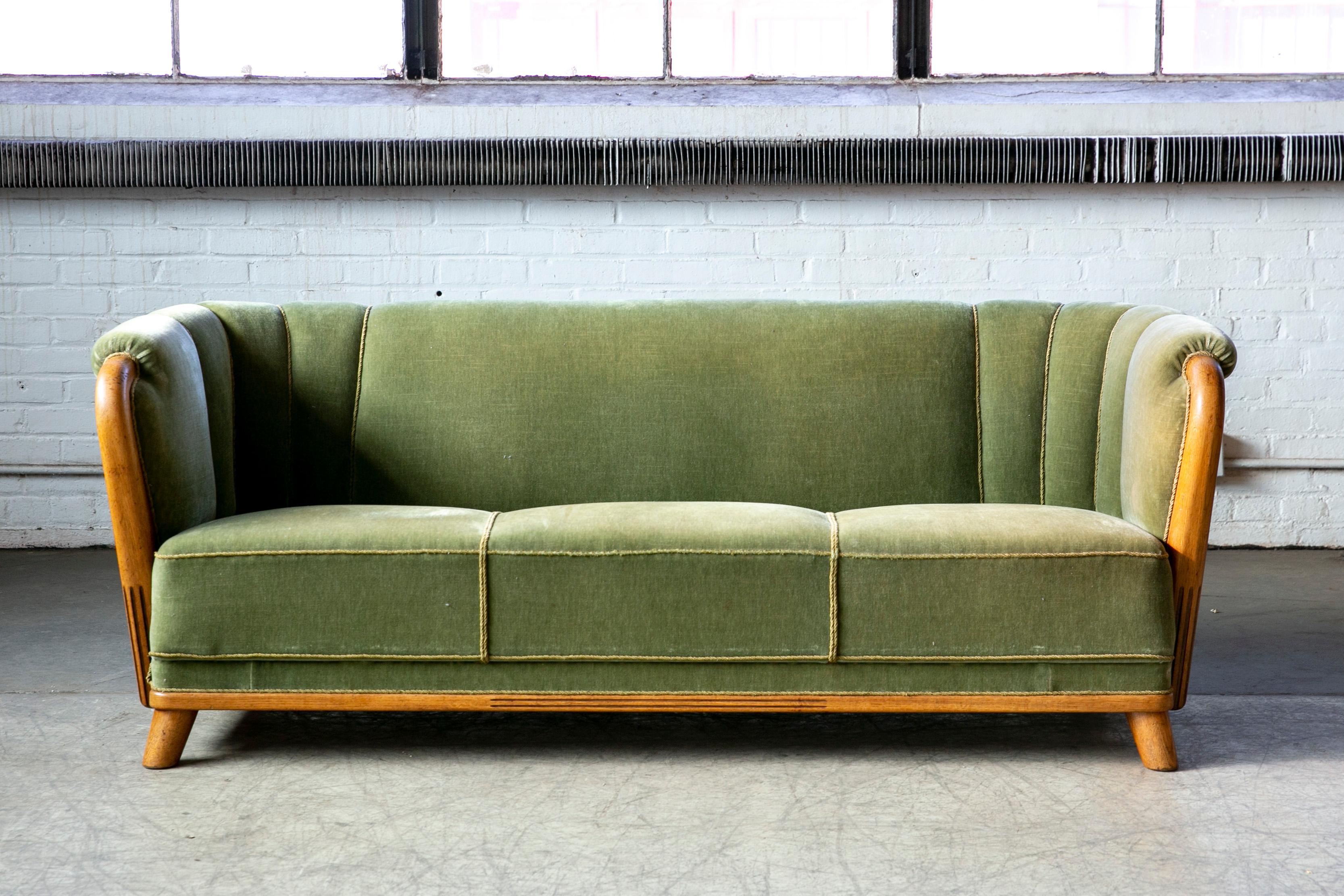 Danish late Art Deco style sofa curved probably made in the late 1930's or early 1940's. This sofa has a really nice elegant lines very reminiscent of Viggo Boesen and we love the combination of the mohair fabric with the channels in and the carved