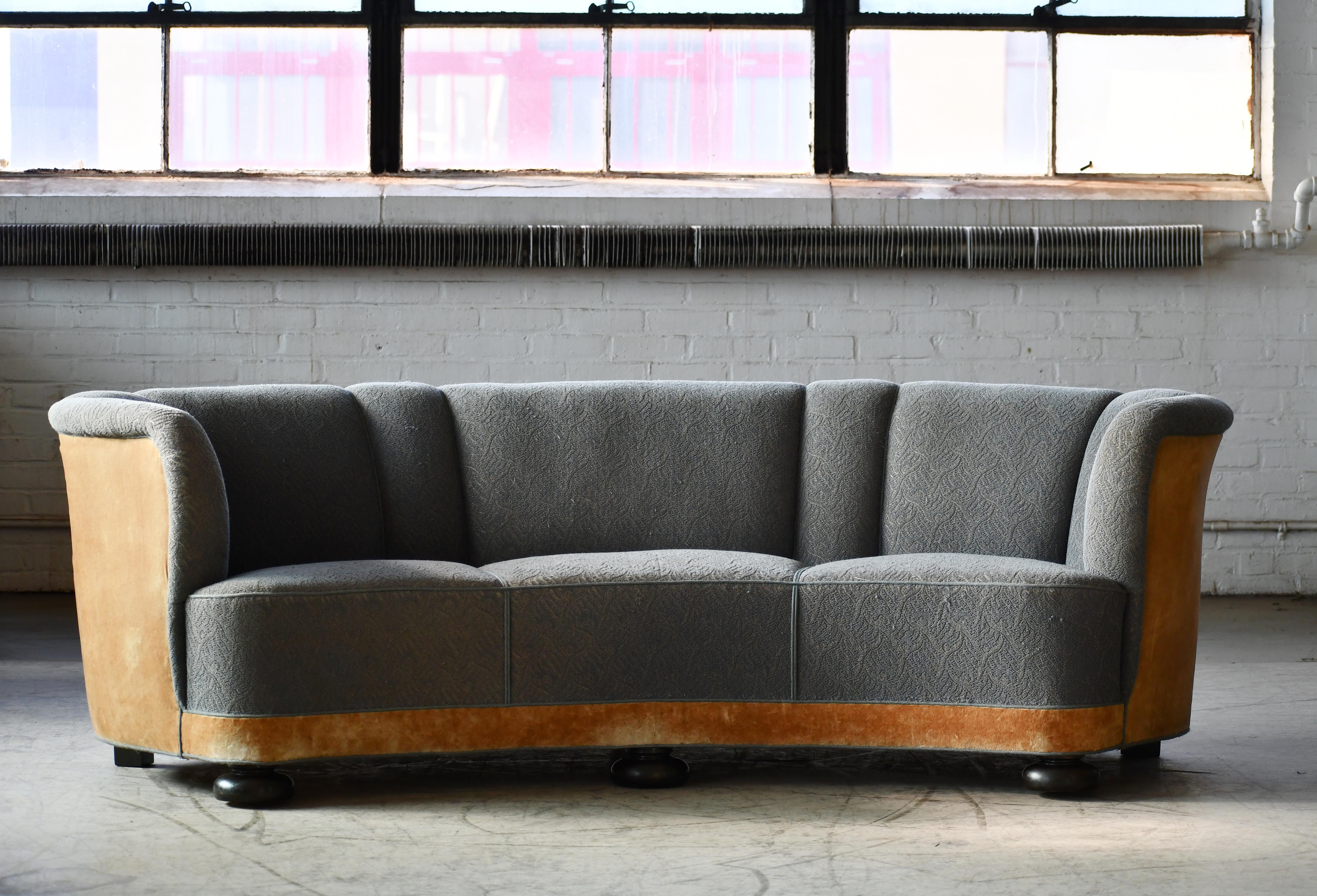 Large banana shaped or curved sofa made in Denmark, circa 1940. This sofa will make strong statement in any room. Beautiful round voluptuous lines and with large bun feet providing a for an elegant and impressive look with it's long length. Somewhat