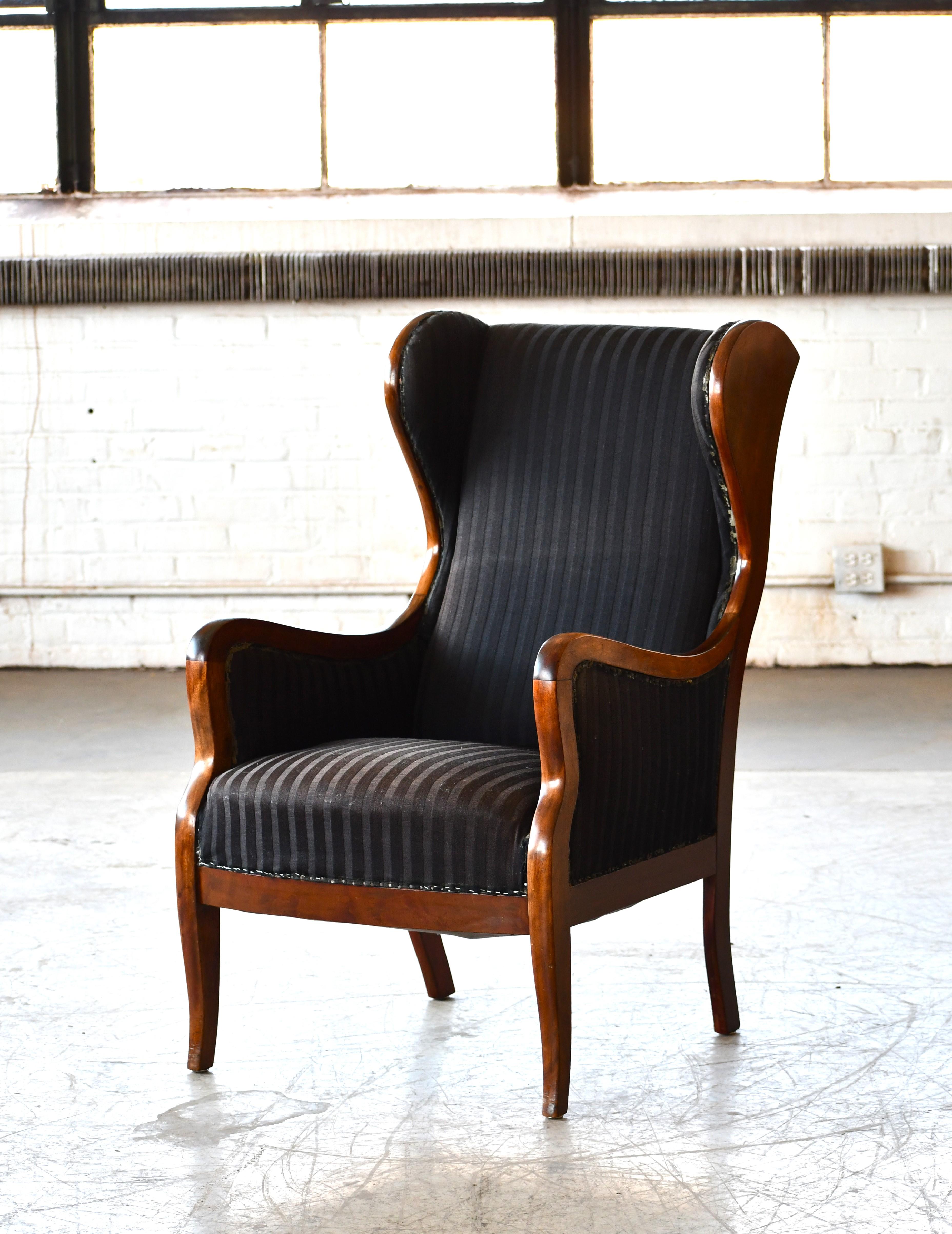 Magnifique chaise à oreilles classique des années 1930-1940 produite par le maître ébéniste Frits Henningsen, Danemark. Glissière en bois de hêtre teinté acajou. Un design très élégant qui s'intègre parfaitement à tout design moderne et qui