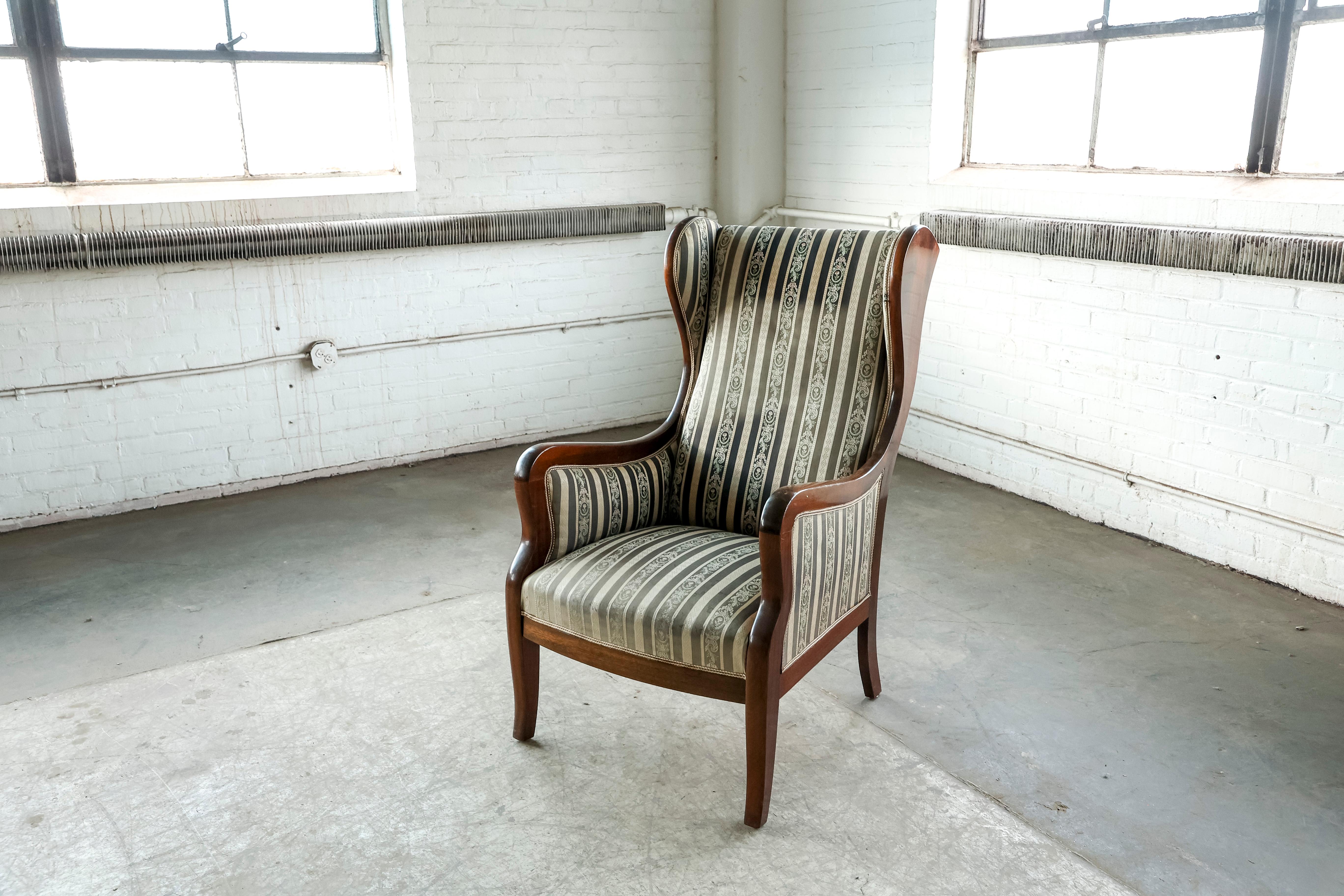 Beautiful classic 1930s-1940s solid mahogany and wool wingback chair produced by Master Cabinetmaker Frits Henningsen, Denmark. Very elegant design that fits superbly into any modern design making a strong yet refined statement. We love the wooden