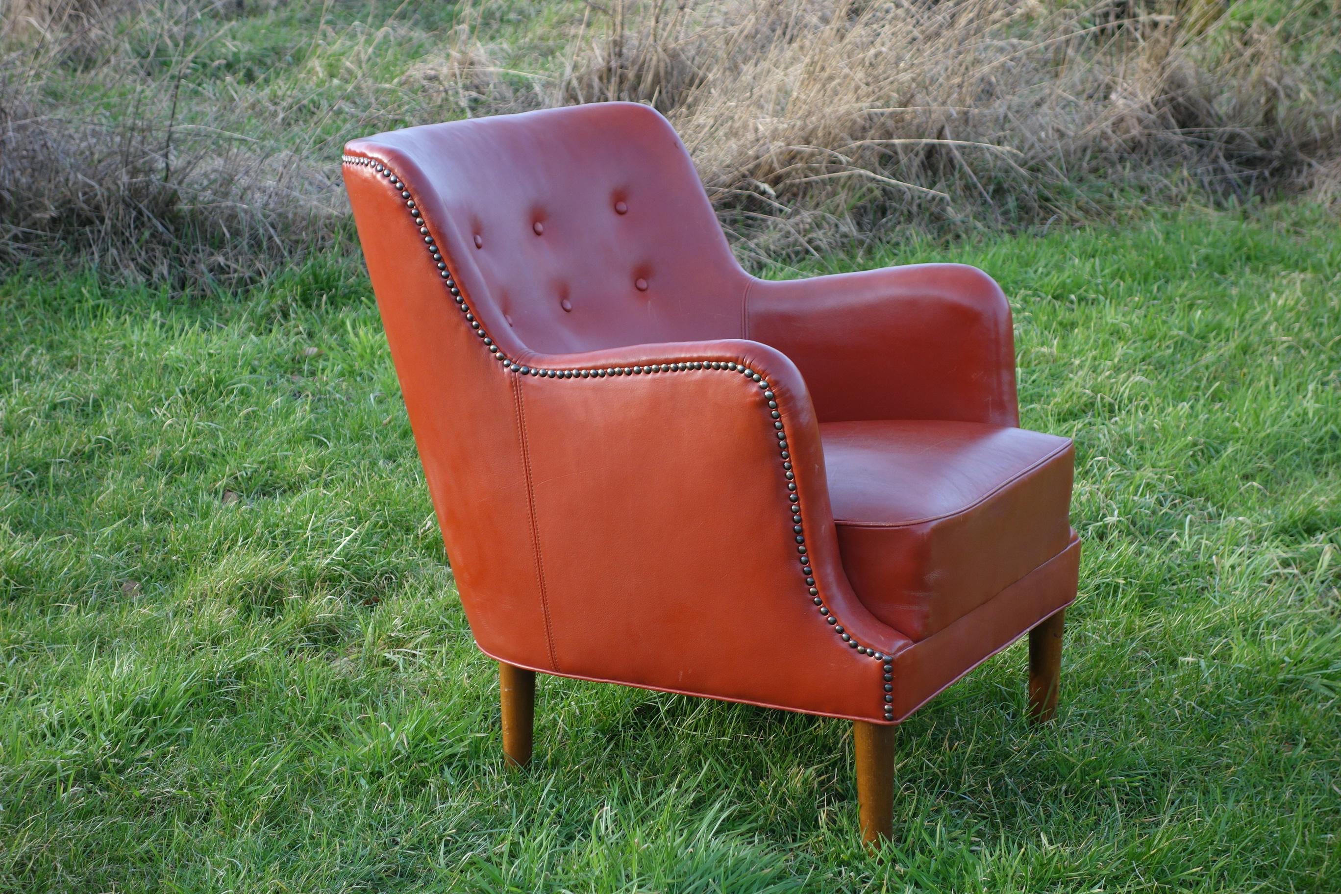 A beautiful Danish leather chair from the 1940s. It is in a strong leather and has a nice shiny patina. Low and organically shaped with brass nails along the edges. It is very comfortable to sit in. It has round legs, which is not often seen on this