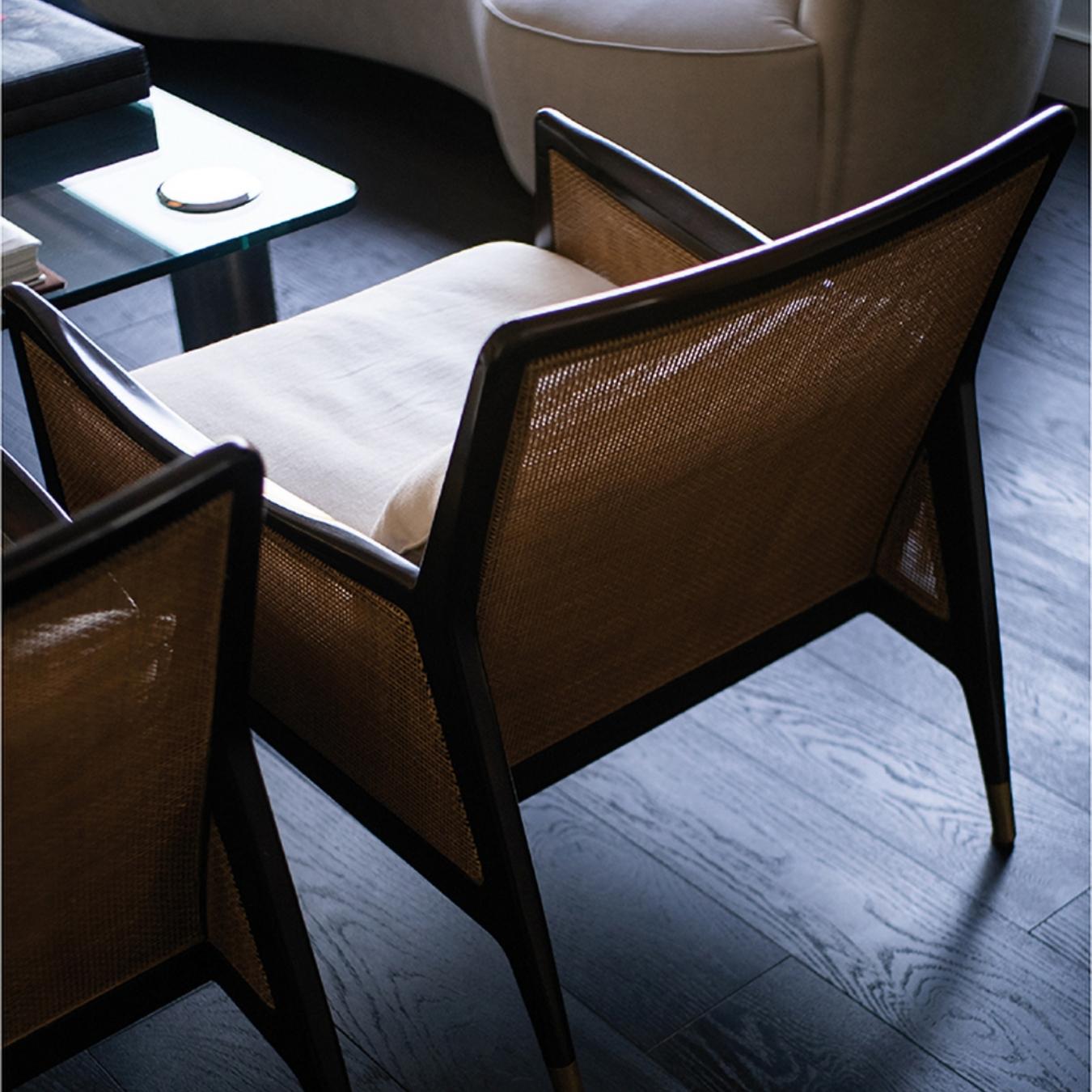 This arm chair is influenced by Danish design that dates from 1950-1960. It has a double caned back and arms, with a loose cushion on the seat and legs with brass caps on the ends.
 