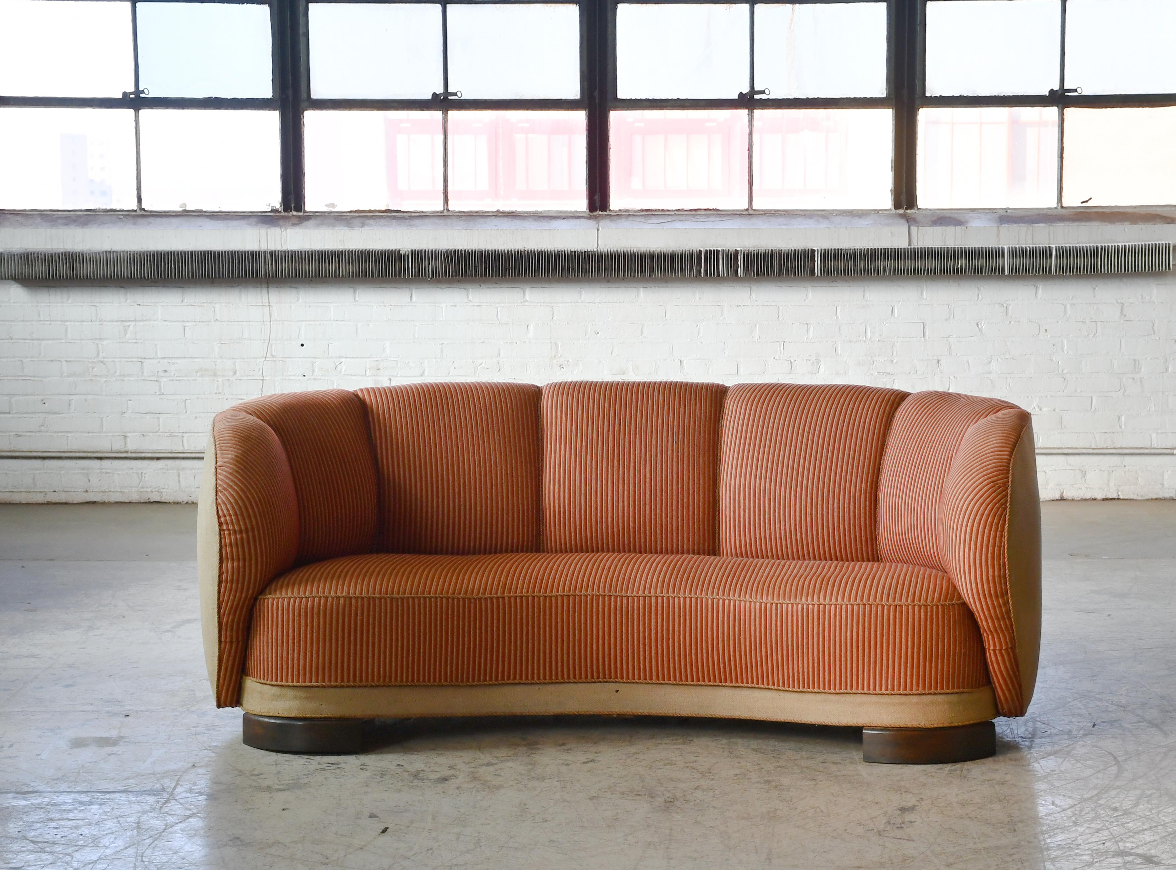 Beautiful and very elegant and organic looking Danish 1930-40s curved two-seat sofa raised on a beech frame and legs. These type of sofas was manufactured from the 30's and up through the early 50's. The 50's versions has somewhat longer legs to