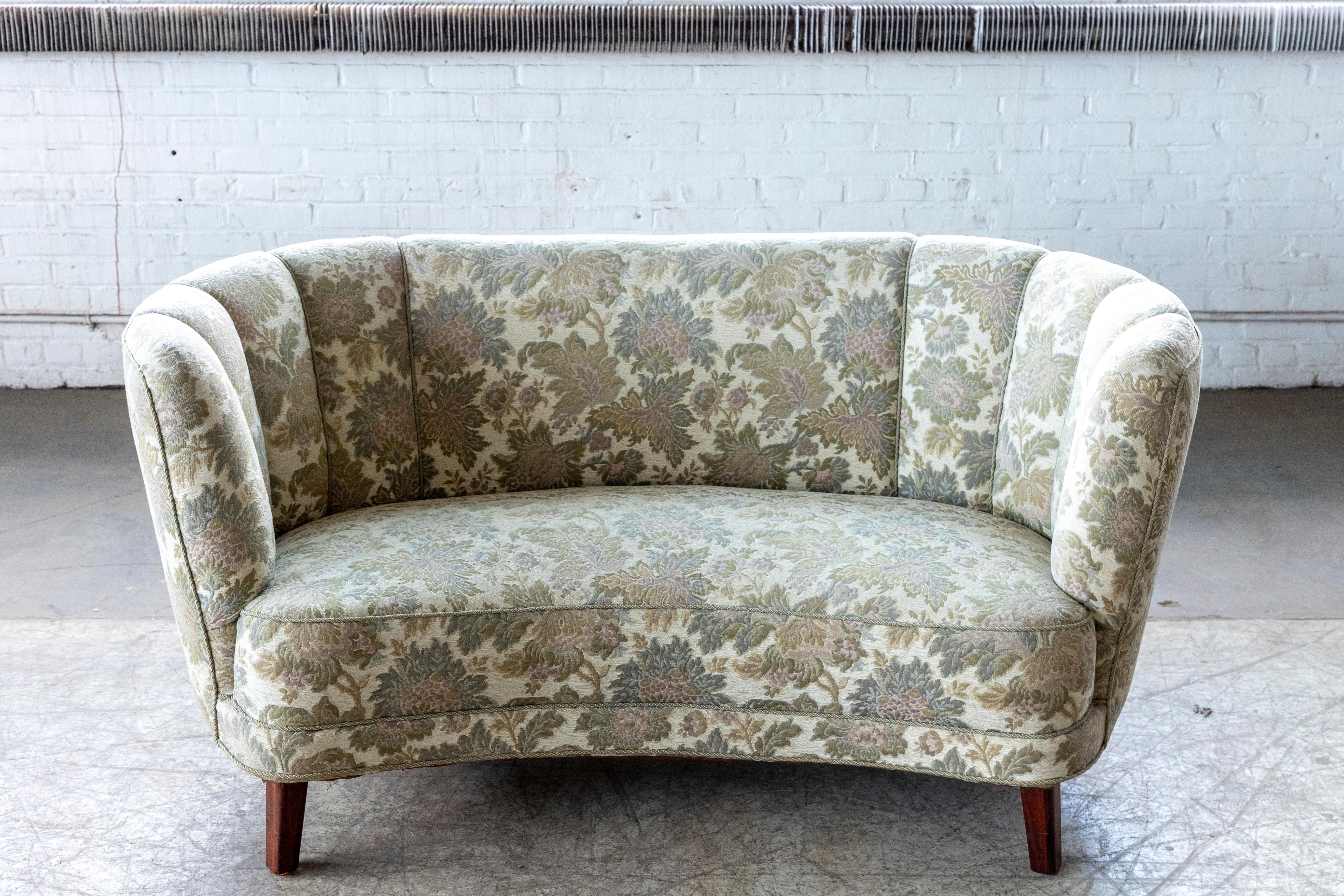 Beautiful and very elegant Danish 1950s curved two-seat sofa raised on a beech frame and legs. These type of sofas was manufactured from the 30's and up through the early 50's. The 50's versions has somewhat longer legs to make them more modern and