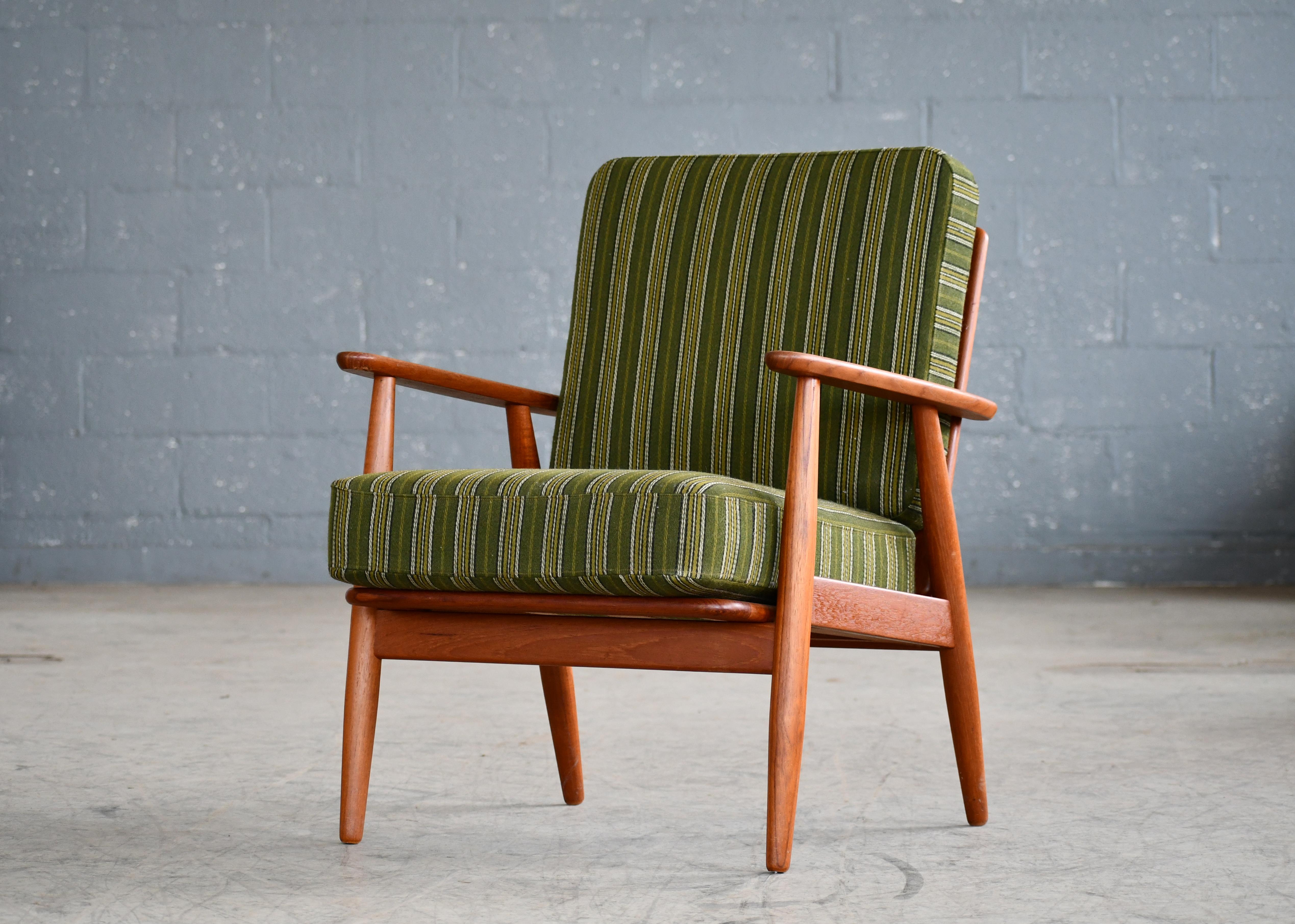 Very charming classic Danish easy chairs from the 1950s in the style of Arne Vodder and Hans Wegner's Cigar chair. Solid teak base with armrests in solid teak and a very nice wood grain and with the original spring loaded cushions. Fabric showing