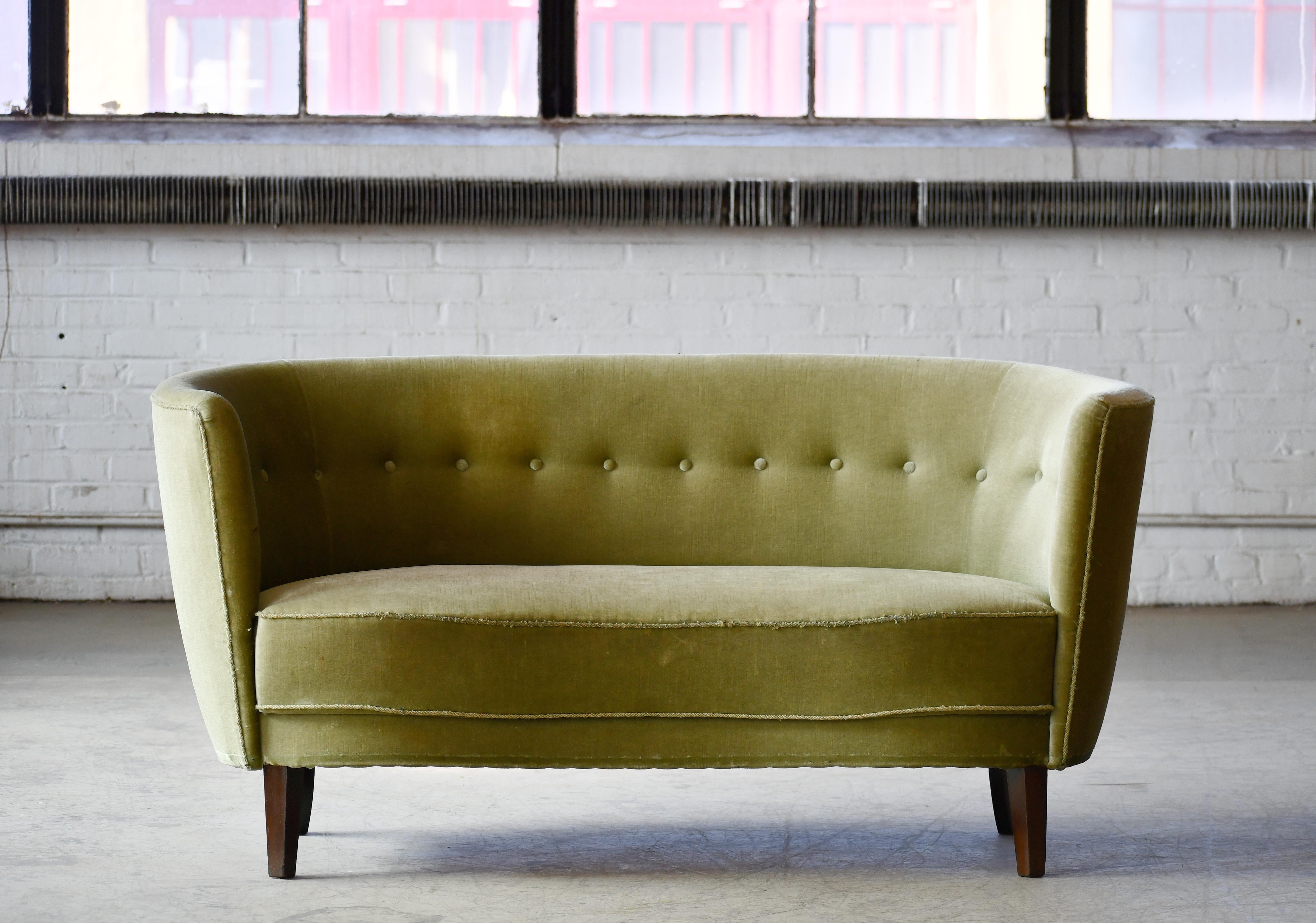 Banana shaped or curved loveseat made in Denmark, around early 1950s. This small sofa will make a strong statement in any room. Beautiful round voluptuous lines and tall legs. These sofas were typically made up through the 1930s to early 1950s and