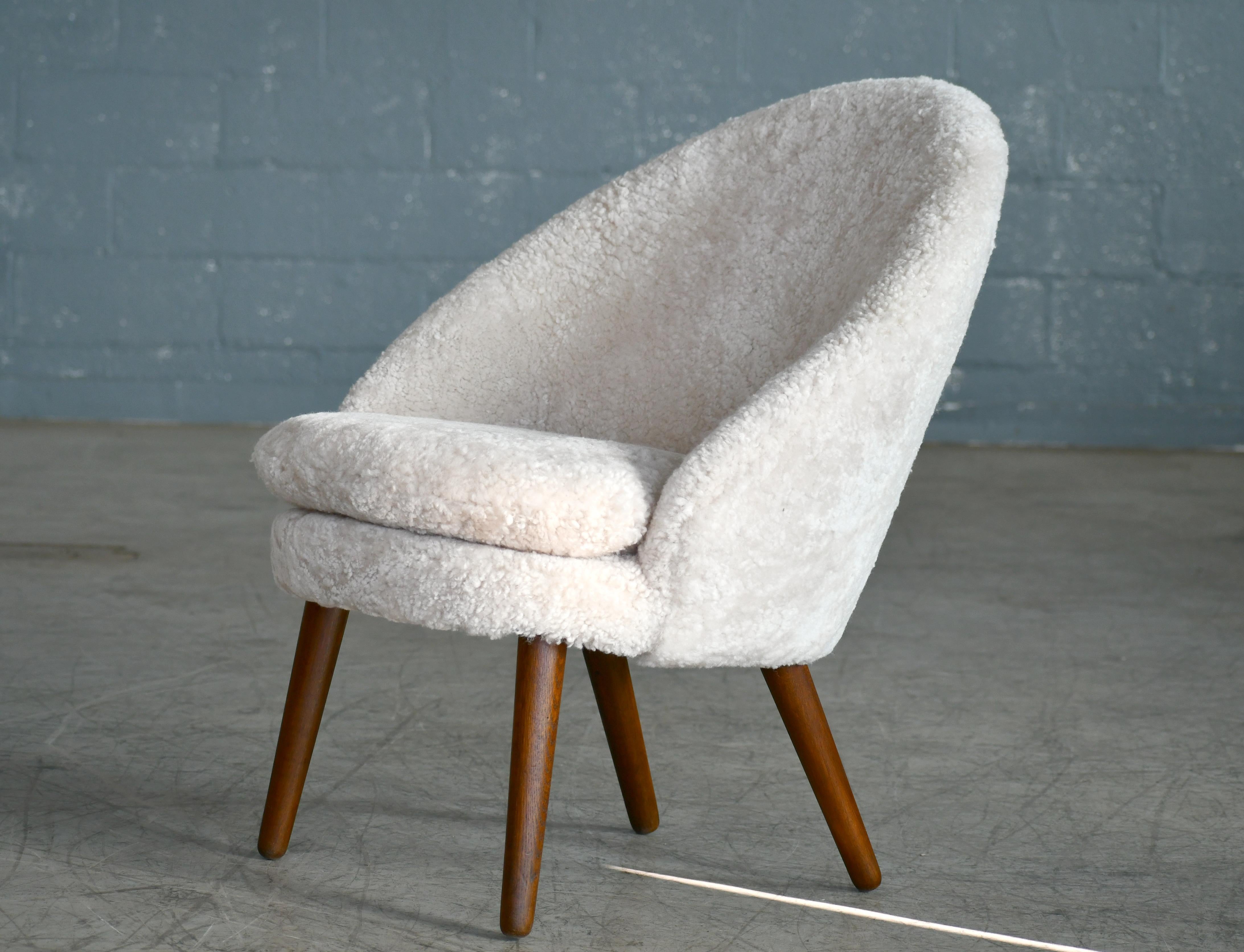 Classic easy chair with curved back and legs in solid oak designed by Ejvind A. Johansson in 1958 as Model 301 for Gotfred H. Petersen. Newly refurbished and re-upholstered in putty colored curly fancy shearling sheepskin from Dualoy. Super