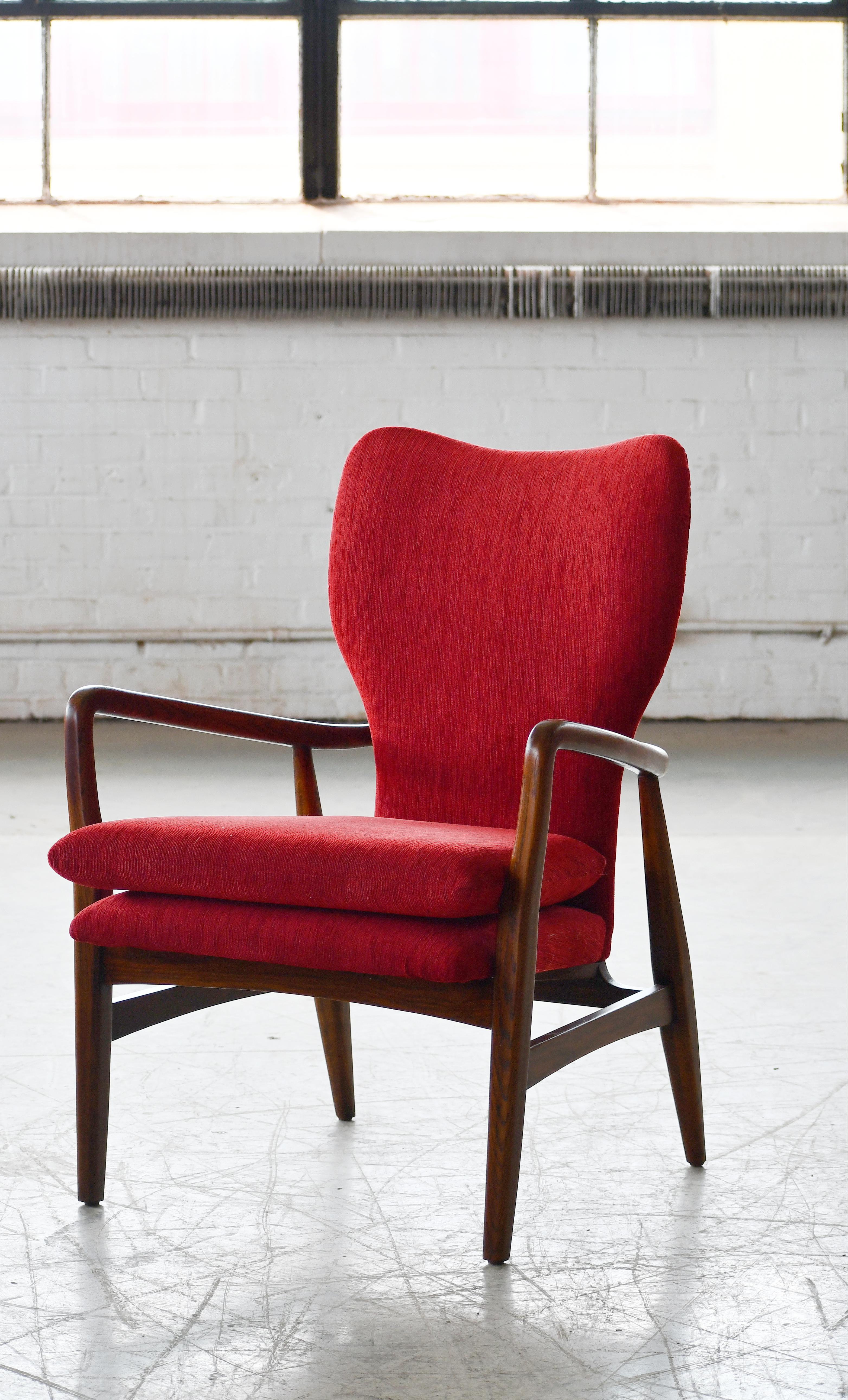 Danish very elegant and sculptural looking chair from around 1950. Upholstered at a later point in red wool. The oak frame has taken on a teak color over the years and stands out with very nice color and grain. 