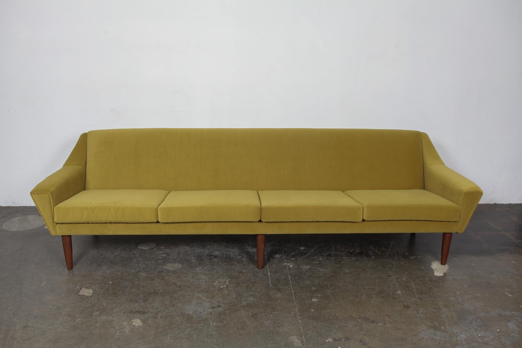 Classically-styled Danish midcentury sofa, circa 1960s. Tight back, loose cushion with beautiful curving style arms gives this a sleek silhouette. Newly upholstered in a green velvet fabric. Sofa sits on 6 solid teak tapering legs which have been
