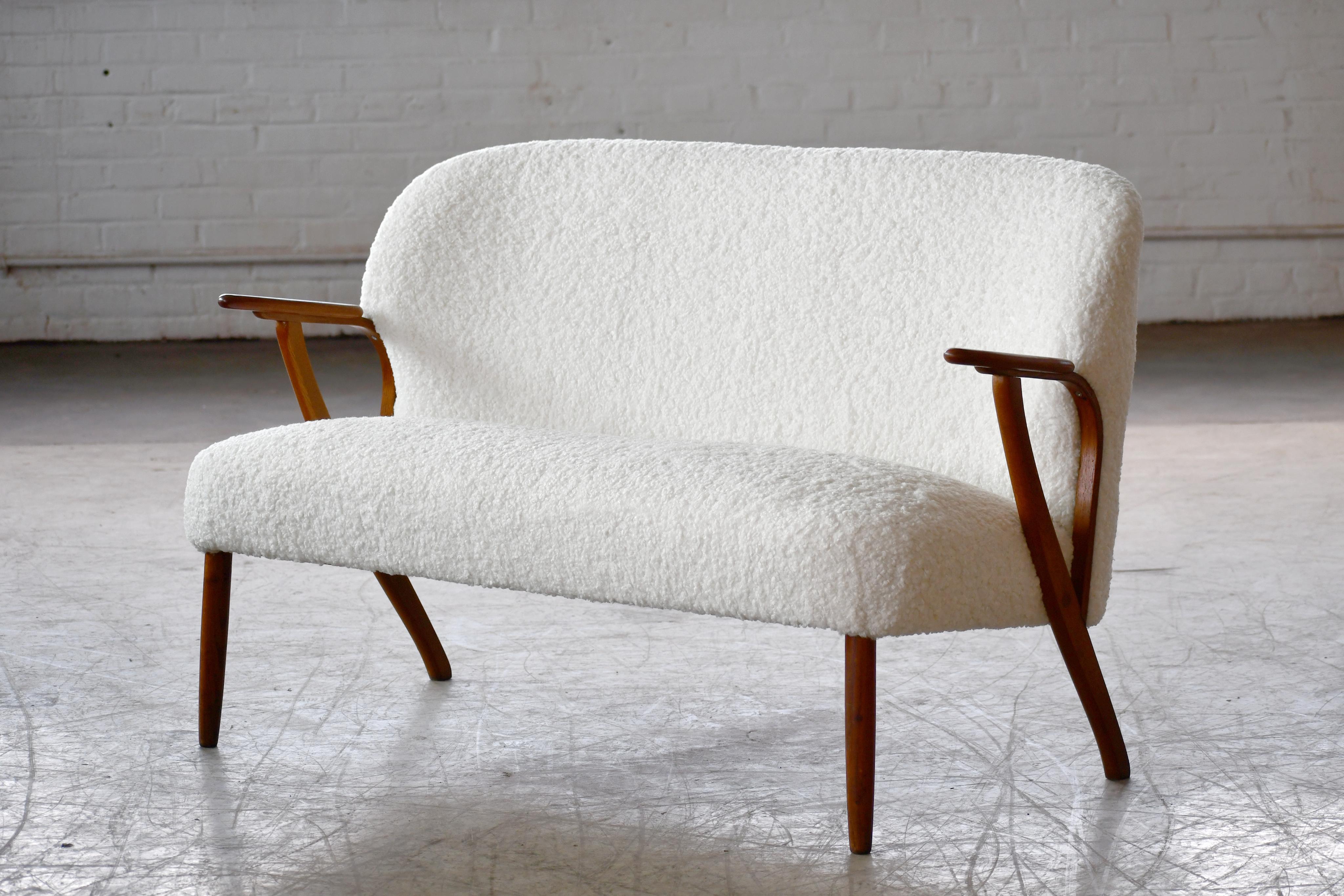 Beautiful and elegant small 1950s Danish settee with legs and armrests in solid teak. The high quality woodwork and design is very much in the style of Arne Hovmand Olsen and generally this piece is attributed to him, however, the attribution has