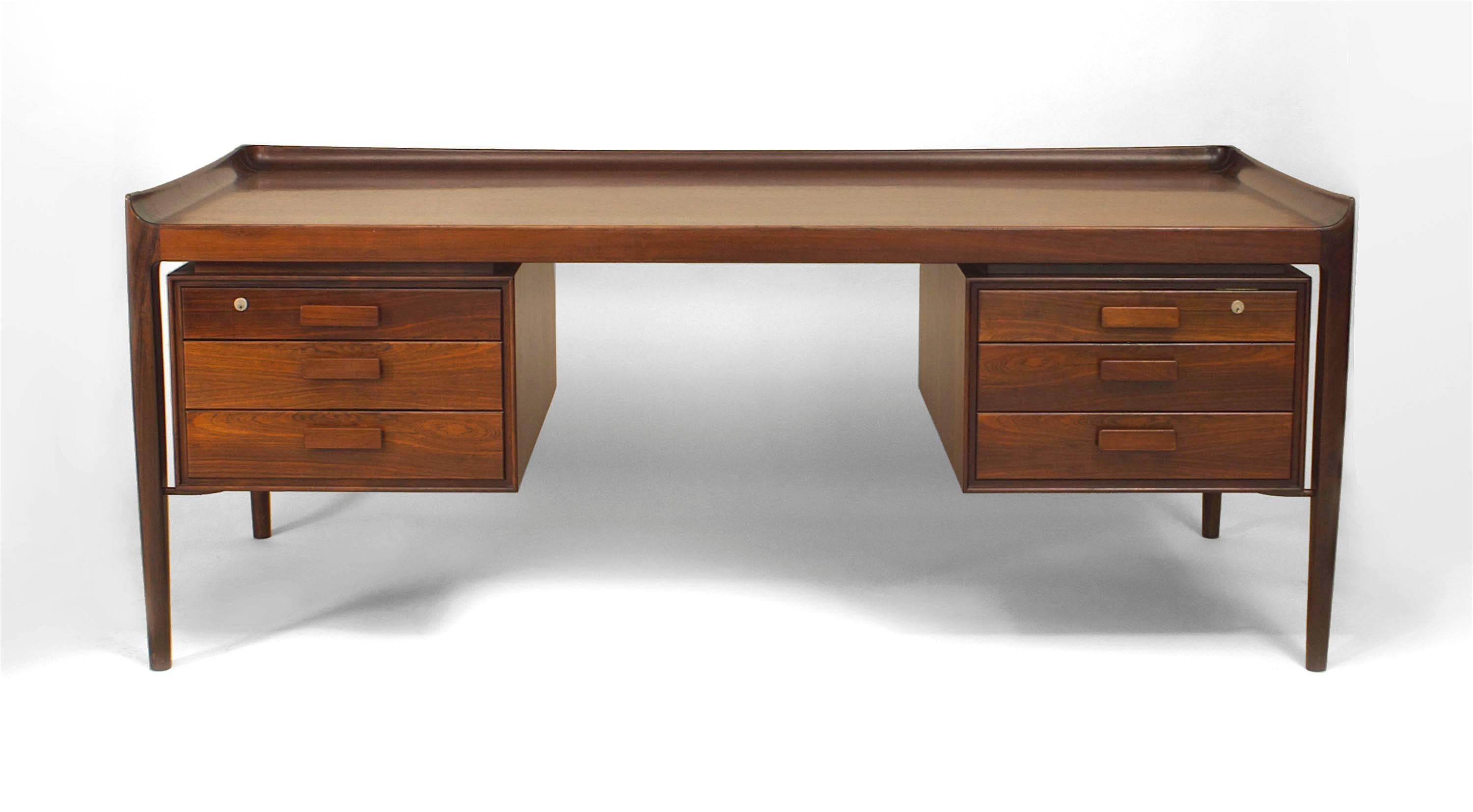 Danish 1950s rosewood knee-hole executive desk with two pair of three drawers on back and a pair of doors on the front with a gallery edge top (Finn Juhl).
 