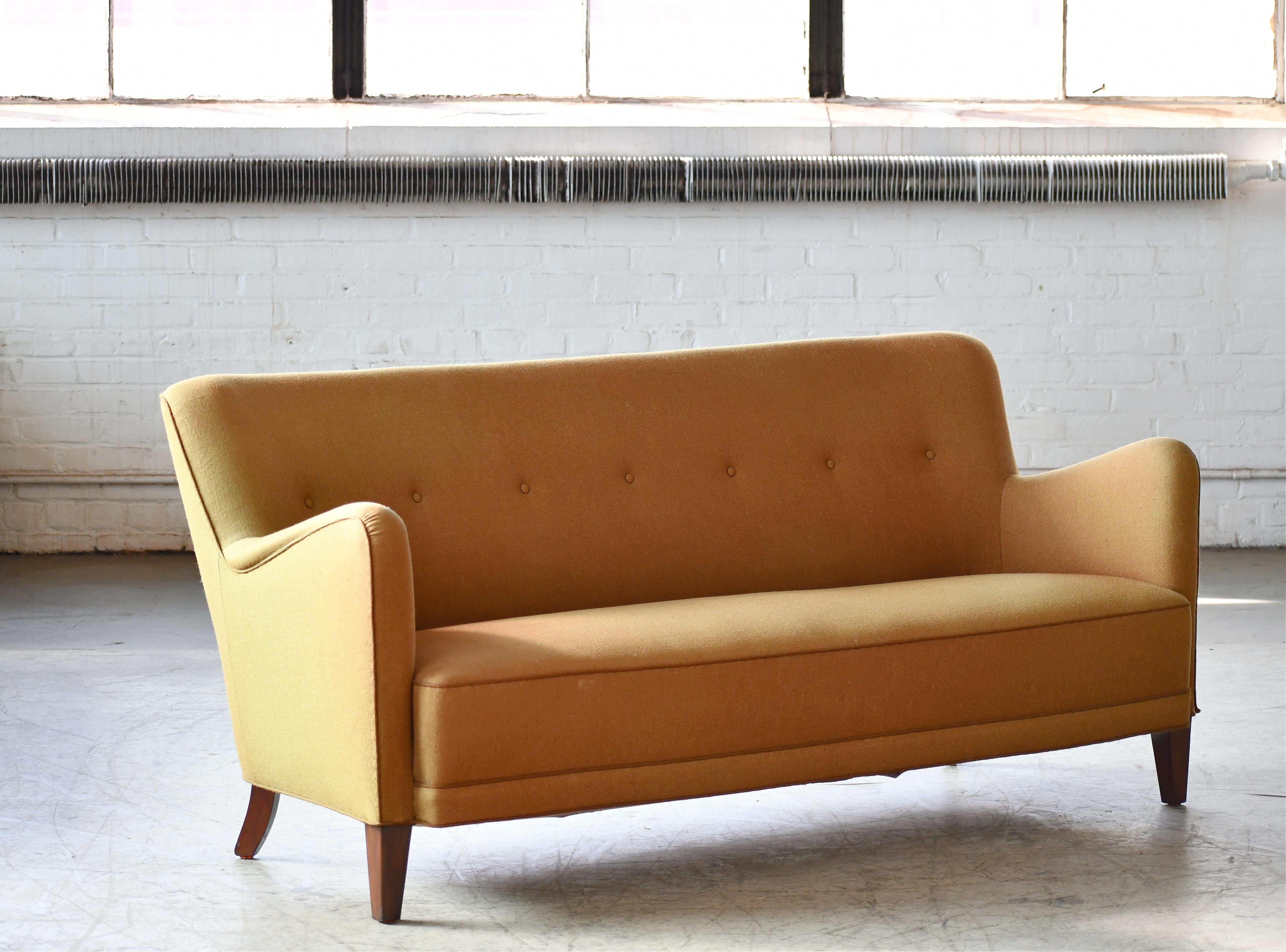 Very classic and ultra cool Danish three-seat sofa epitomizing the 1950s and likely a variant of Fritz Hansen's famous model 1669. Just the shape of the legs vary slightly from the 1940s original. Built on a sturdy beech wood frame and raised on