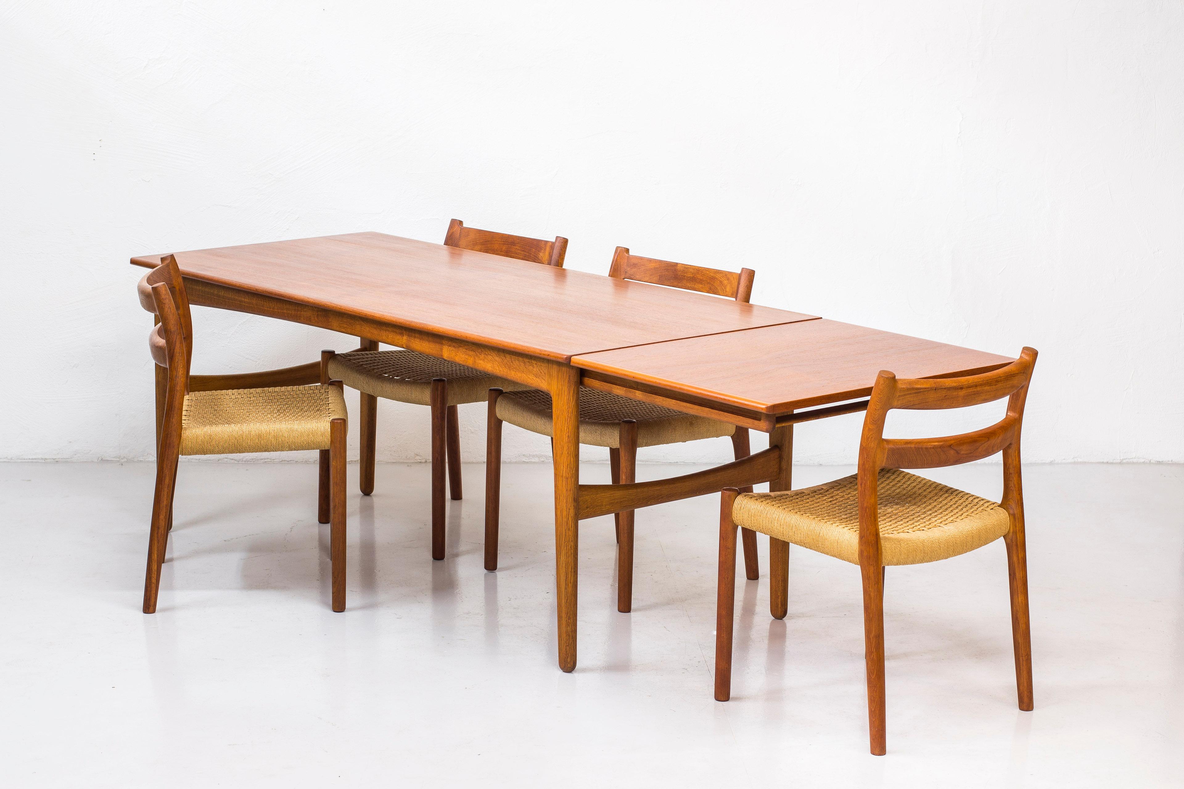 Dining table design by Knud Andersen in Denmark during the 1950s. Produced by cabinet maker J. C. A Andersen. Solid oak legs with teak tabletop. Tabletop extensions on each side hidden underneath the main table. Sits eight to ten people with ease.