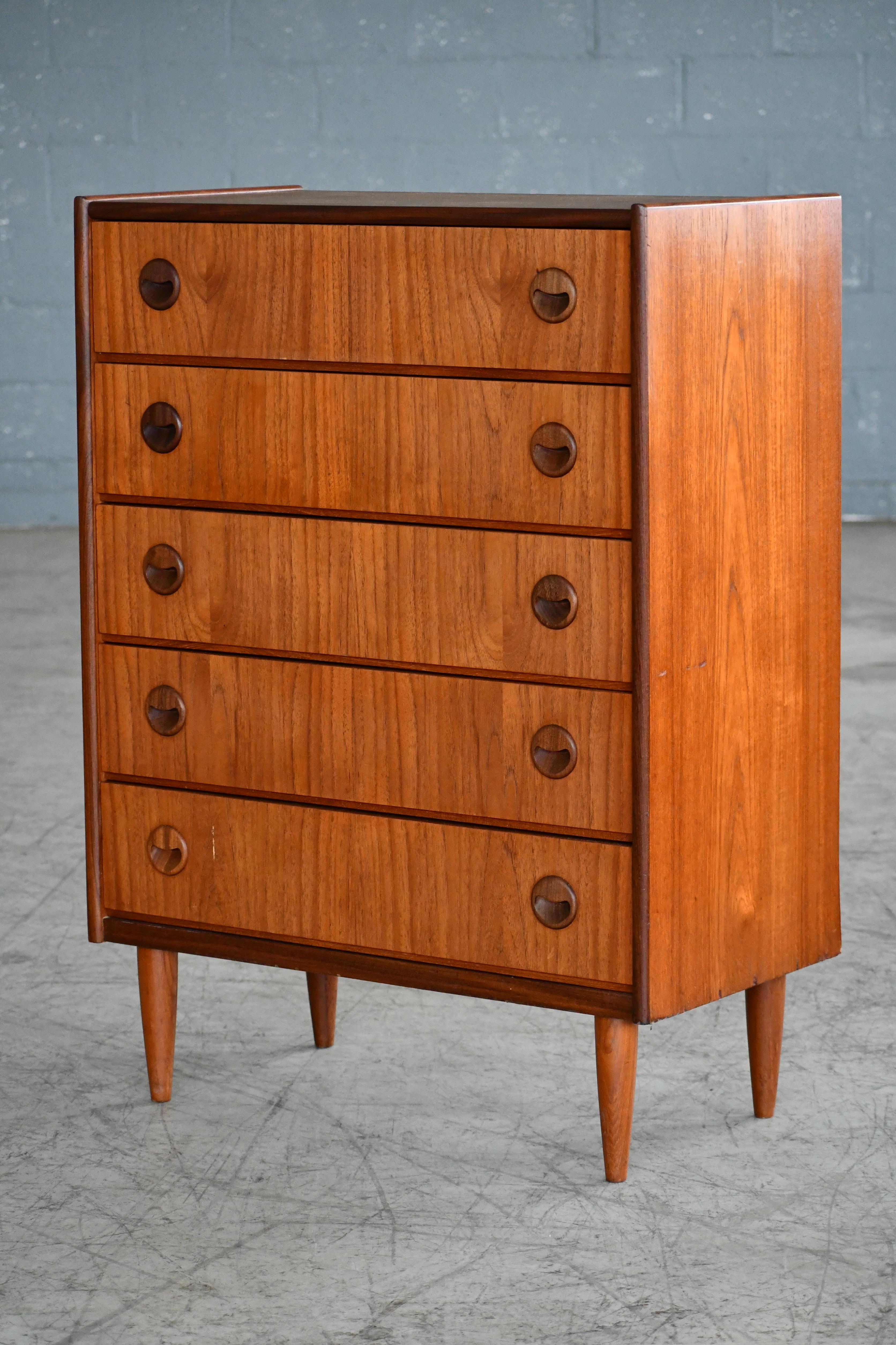 Beautiful Danish 1960s teak tall dresser or chest or drawers attributed to Kai Kristiansen. Sharp distinct design lines and carved round pulls distinct of Kai Kristiansen. Teak veneer with edges of solid teak and pulls carved from solid teak raised