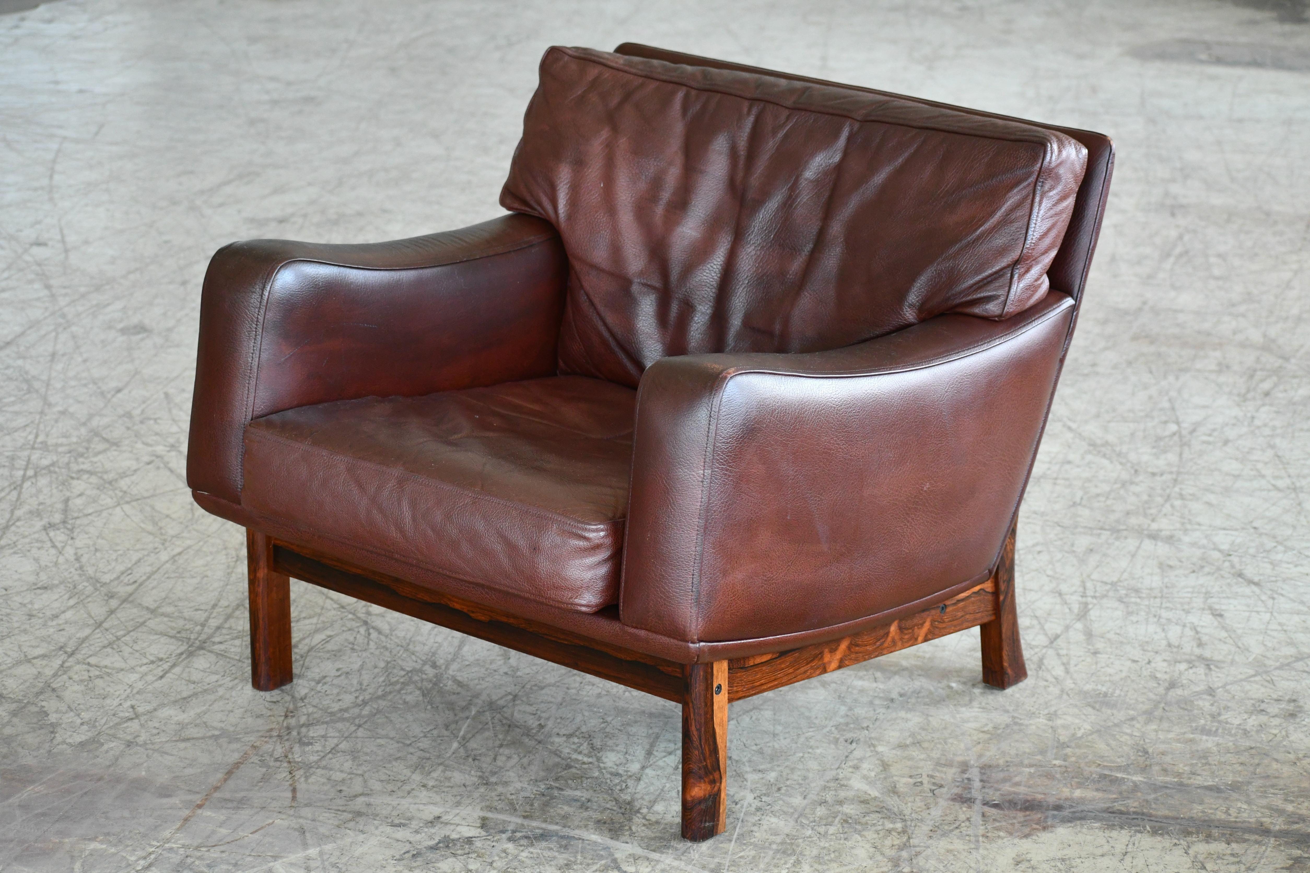 Fantastic Danish modern lounge chair designed and manufactured by Erhardsen & Andersen (Eran) in the late 1960s. The design is low and wide and epitomize Danish design of the late 1960s. High quality buffalo hide raised on a frame and legs carved of