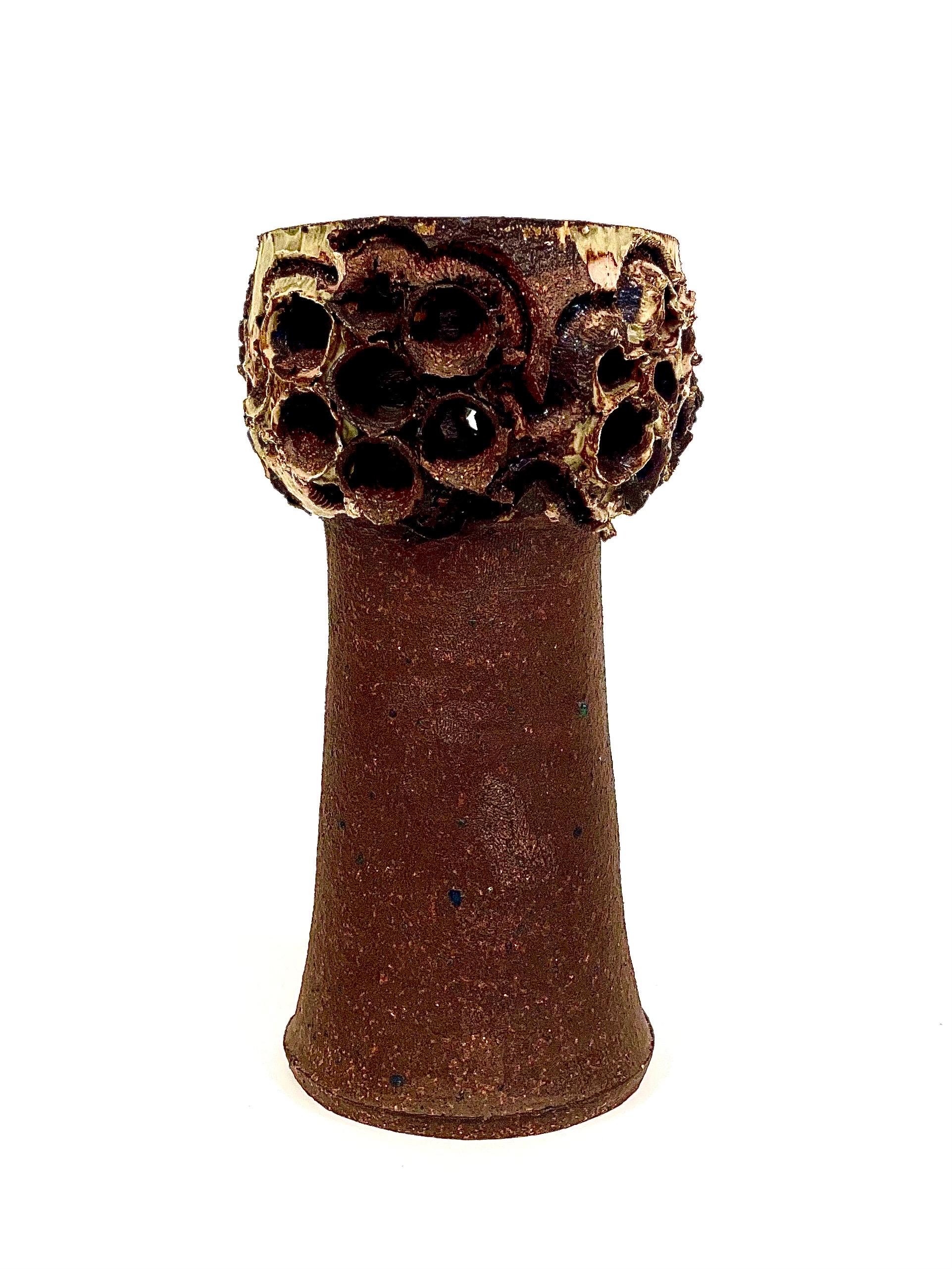 Si tratta di un vaso in gres smaltato al sole, molto strutturato, dell'artista sperimentale danese Bodil Marie Nielsen.
Si presenta con un design brutalista, color mattone e smaltato a fuoco.
Ha la forma di un fungo con gambo affusolato coronato da