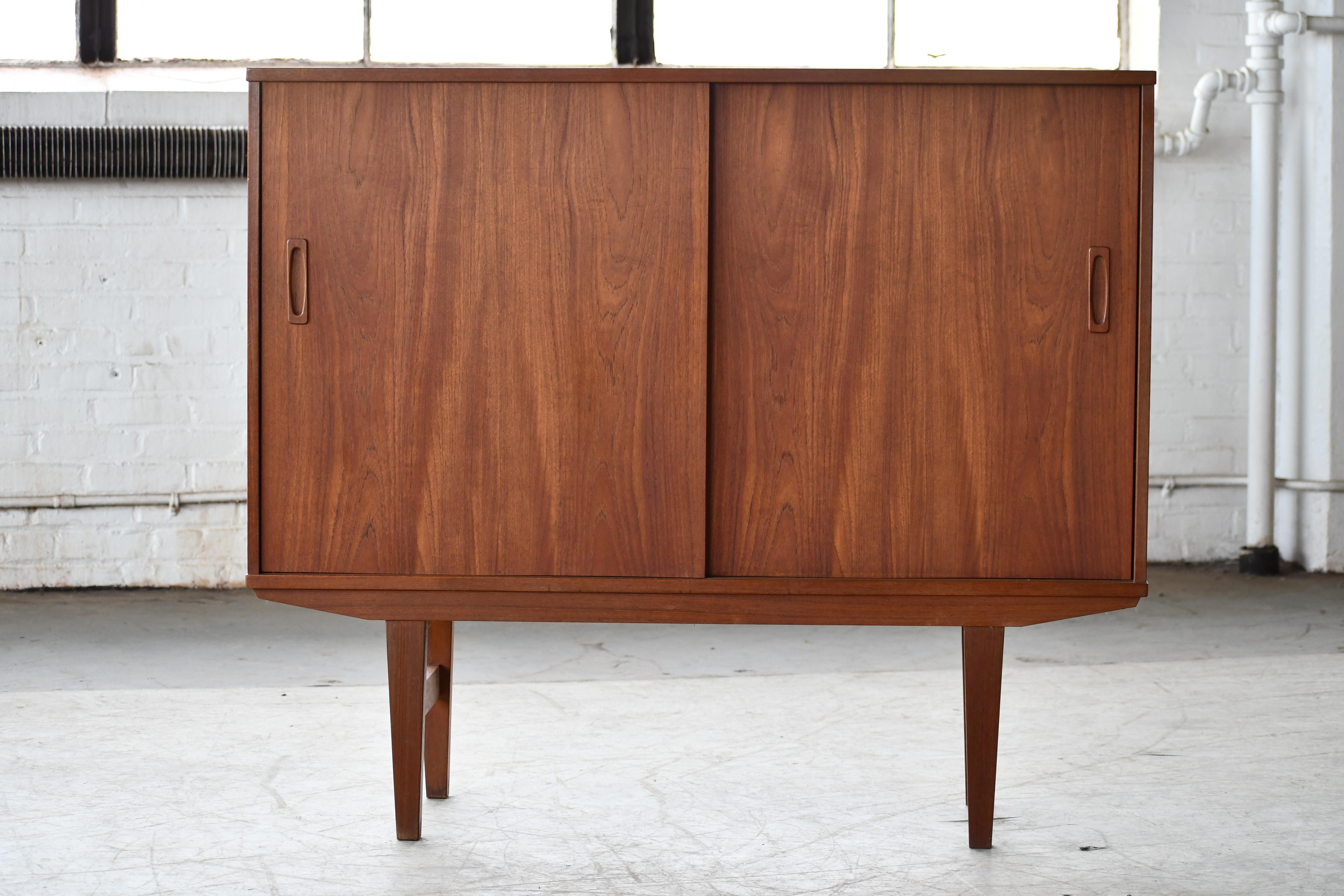 Small charming Danish Sideboard made from teak sometime ion the 1960's. The piece is unmarked and we are unaware of the designer and maker. Nice with drawers inside for cutlery make in a contrasting maple. Small bar with mirrored back in patterned