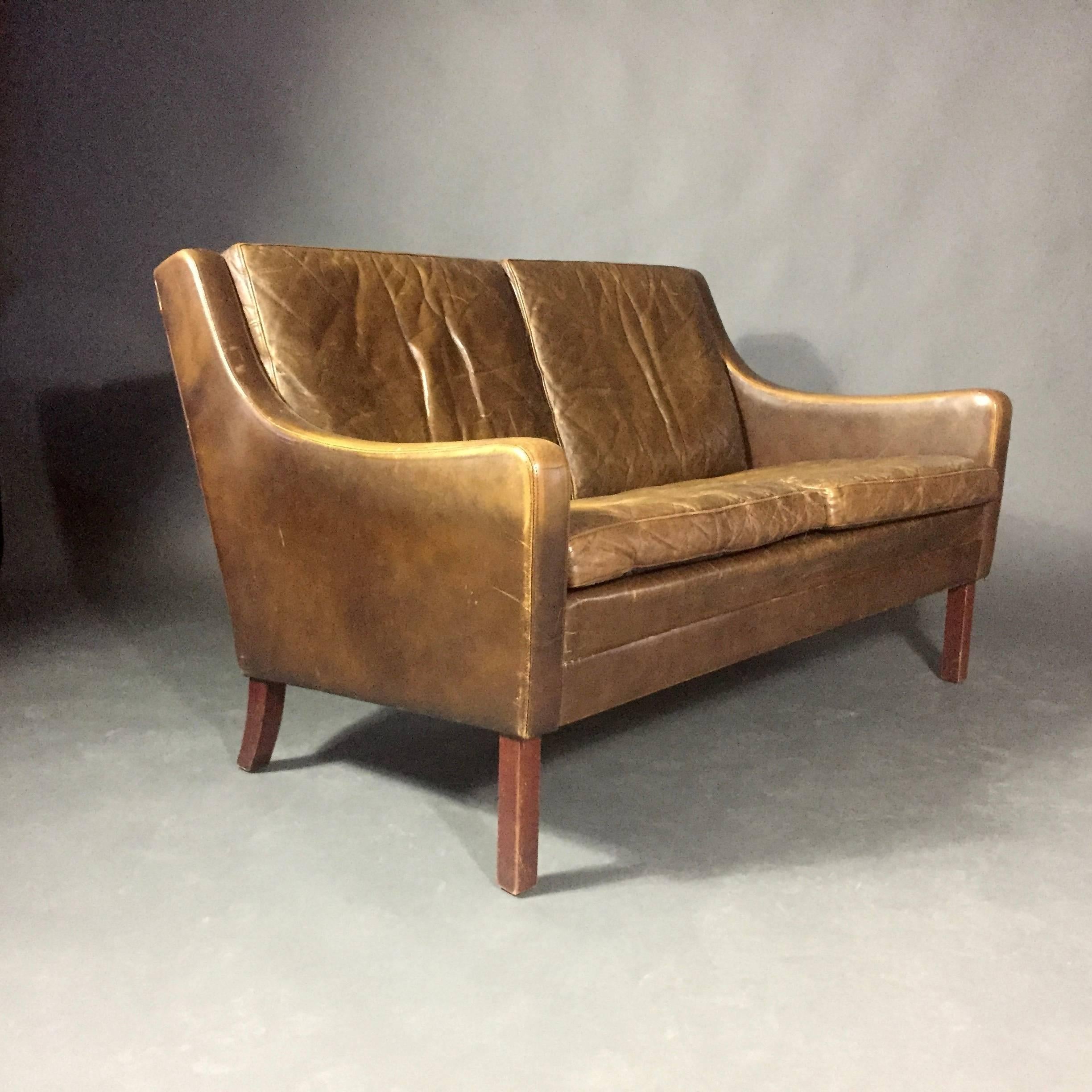 The vintage patina to the cognac leather has to be seen in person to appreciate the perfect wear on this two-seater sofa. If you looking for that gorgeous worn leather look - in otherwise terrific condition. New dust catch to the underside. Danish