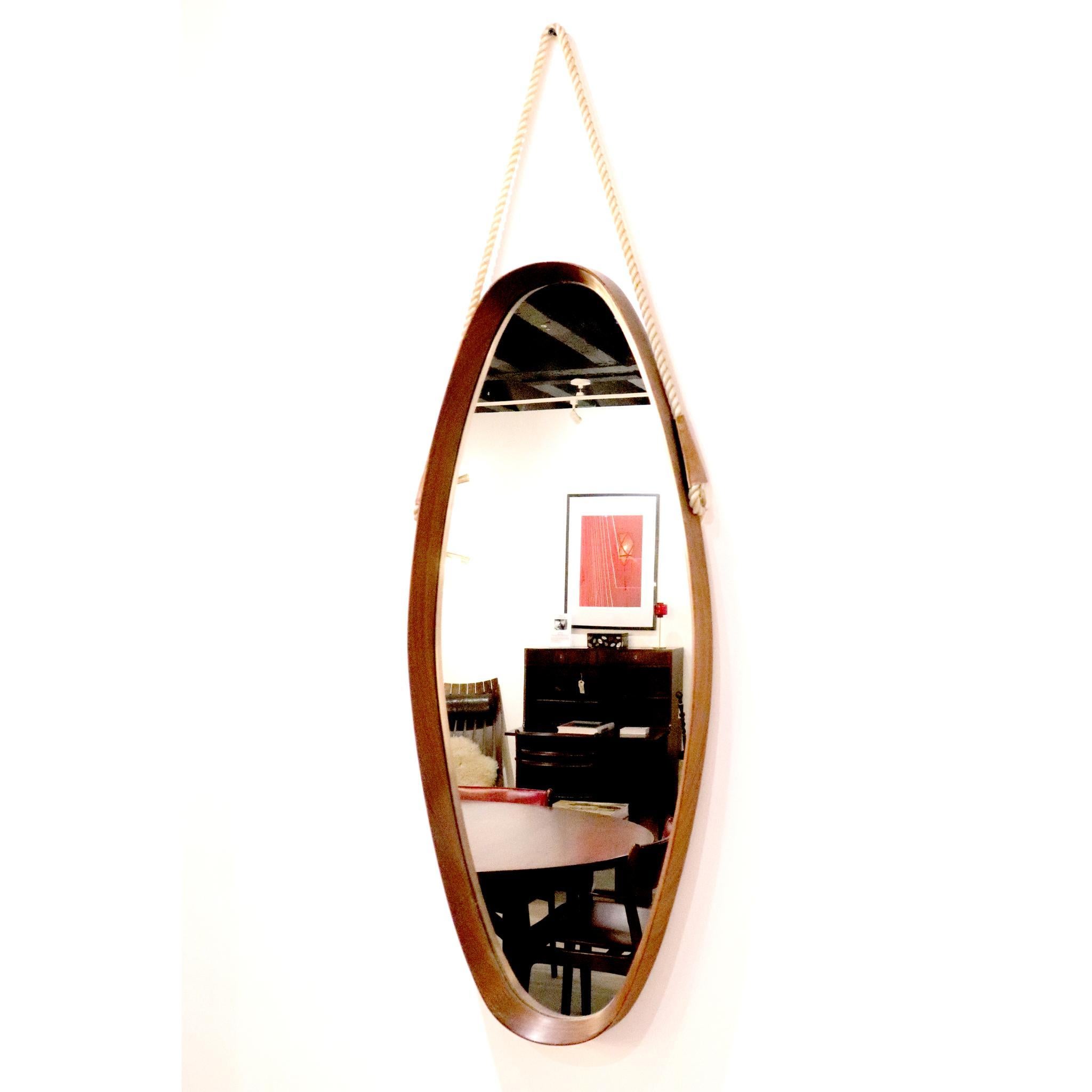 An original 1970's Danish mirror. 
Hung by twisted rope and leather & brass clasps, the teakwood oval shaped frame holds the mirror which is in excellent vintage condition. 
 
Dimensions:
Width: 33cm
Height: 82cm
Depth: 4.5cm.