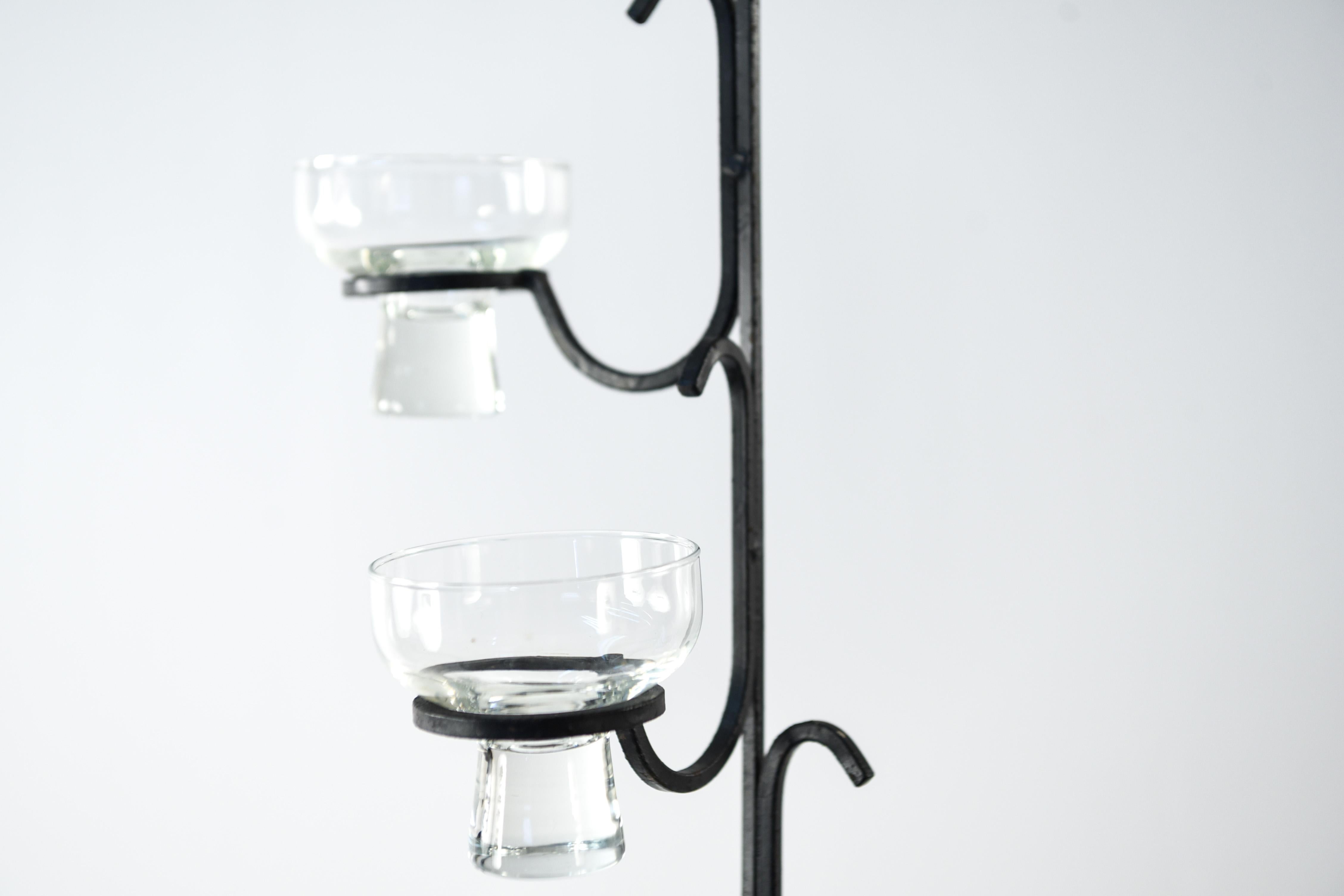 This 1970s Danish chandelier has an interesting vertical form made of steel. This piece features glass inserts to hold candles and has a charming, rustic appearance to it.
