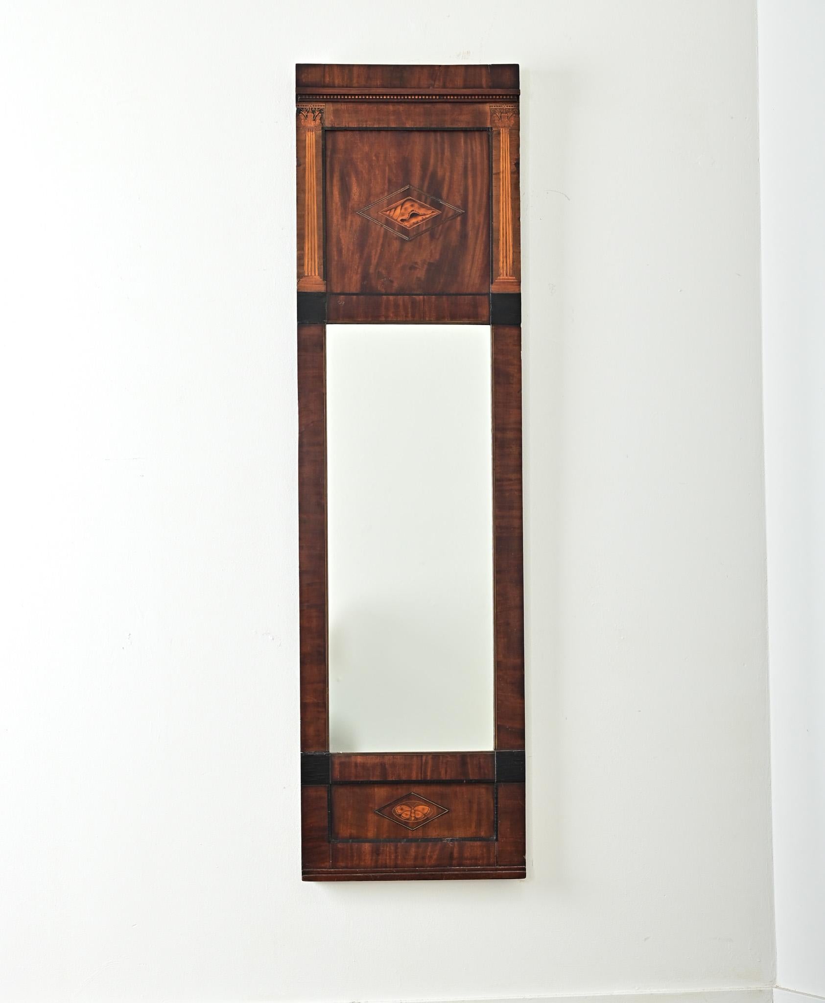 Fabulous 19th century tall and narrow mahogany mirror, likely from Denmark, expressing both Georgian and Biedermeier tastes throughout the carved, ebonized, and inlaid frame. Marquetry inlay as gorgeous Corinthian columns of maple wood bookend the