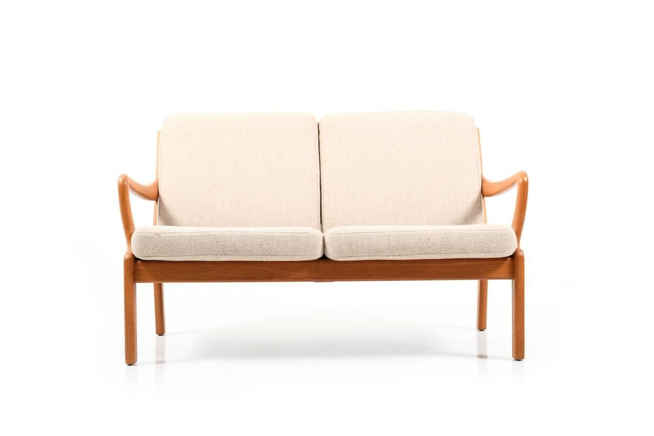 Danish two-seat sofa in solid teak. Seats with cushions in fabric. Denmark, circa 1970.
