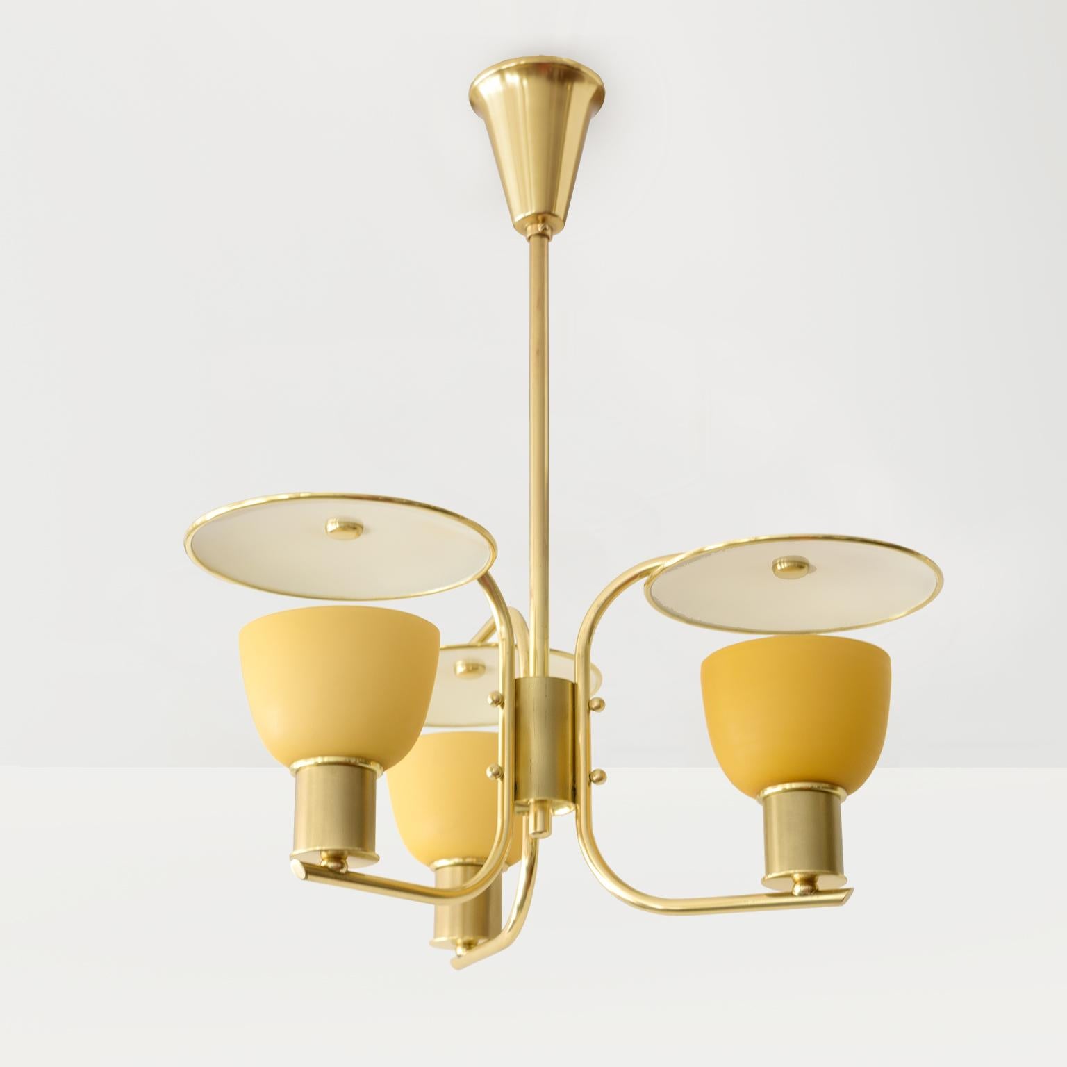 A Danish, 1940’s polished brass 3-arm chandelier with amber glass shades. The brass frame consists of 3 “C” shaped arms each suspends a brass reflector disk which is lacquered on one side. Newly polished and lacquered and required with 3 standard