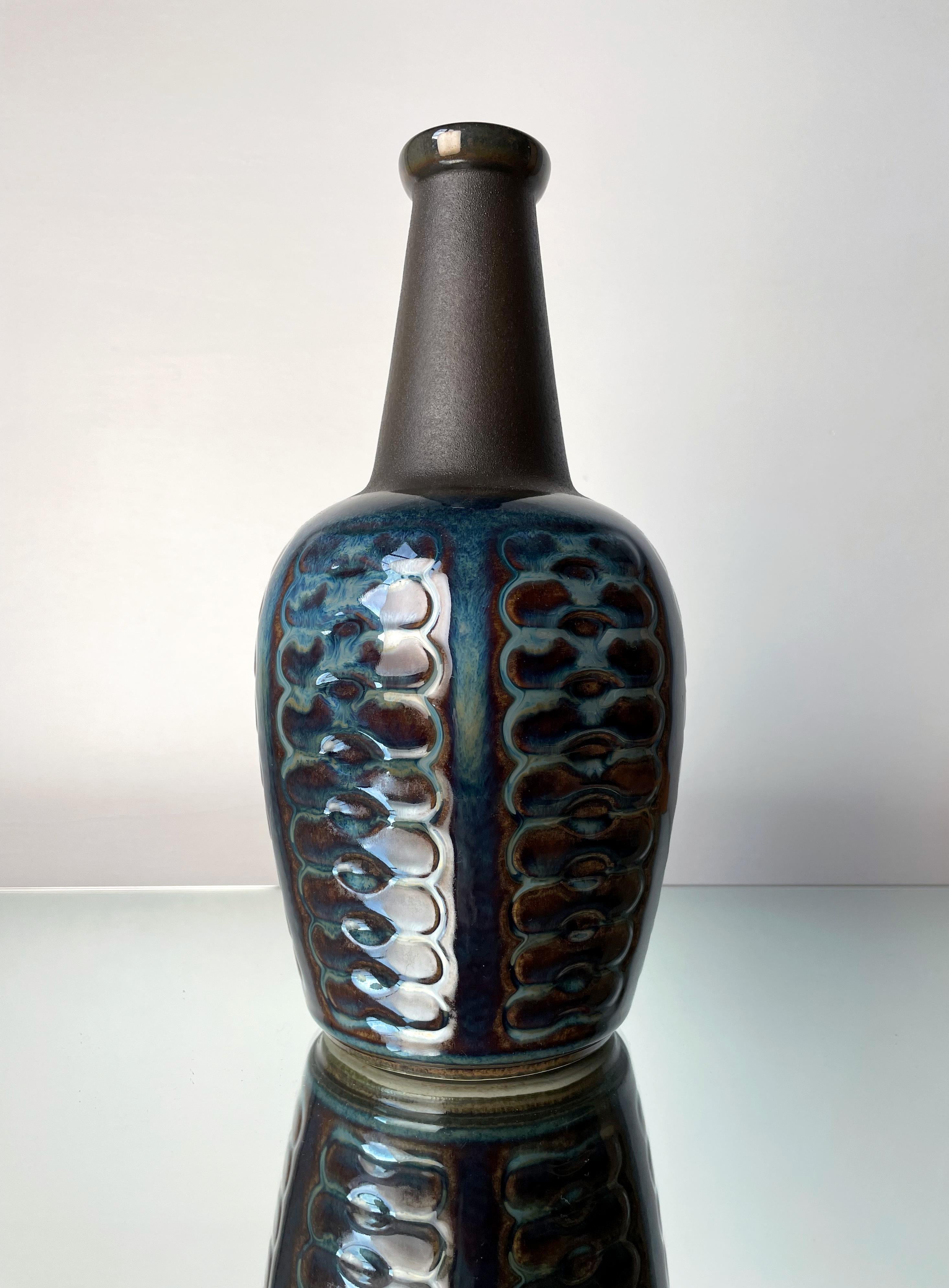 Chubby bottle shaped ceramic vase by artist Einar Johansen. Handmade graphic relief decor with running glaze in blue, light green and caramel colors around the belly as well as on the inside. Matte unglazed black neck. Manufactured on the Danish
