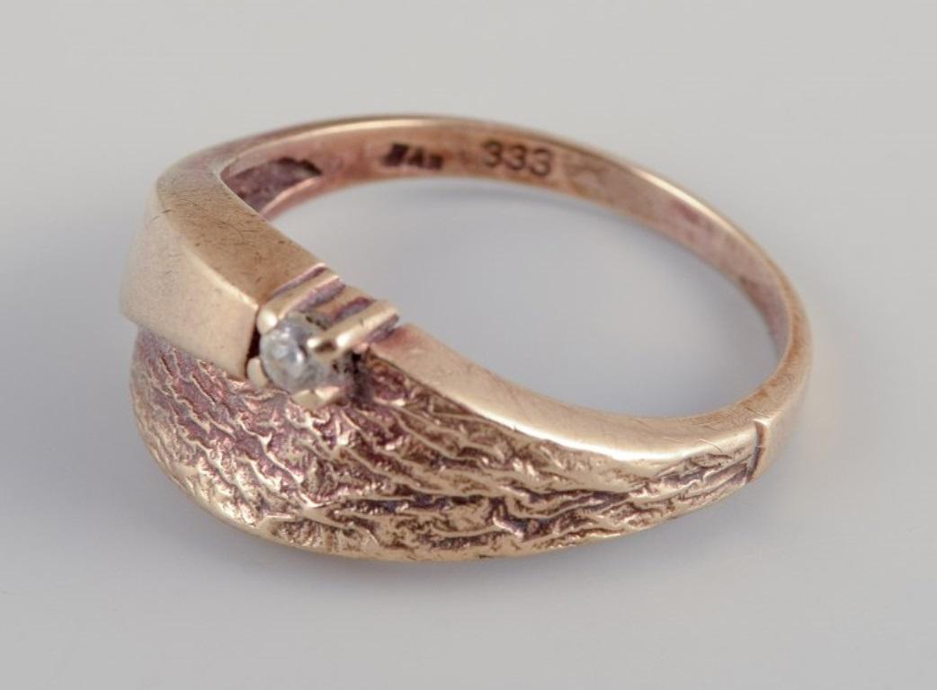 Bague danoise en or 8 carats.
Orné d'un diamant taillé en brillant.
Design/One.
Depuis le milieu du 20e siècle.
Poinçon de maître indistinct.
Parfait état.
Dimensions : 19.5 mm / Taille US 9.5