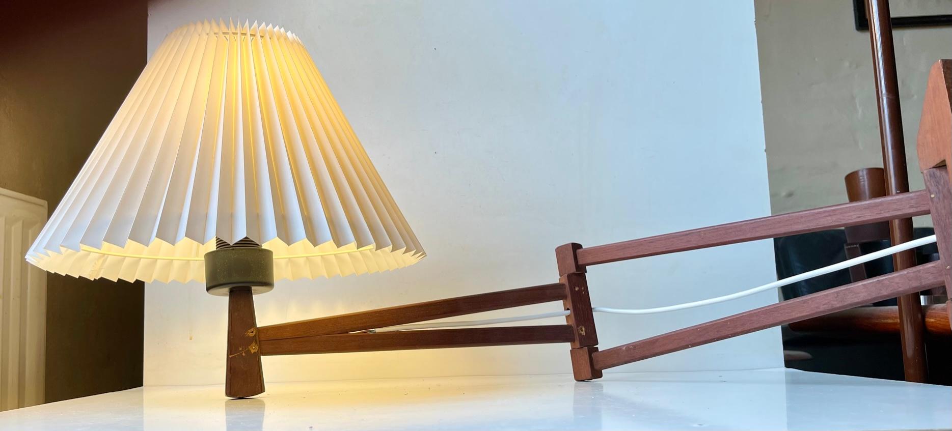 Dept/reach adjustable wall sconce made from teak. Made by ABO in Denmark during the 1970s in a style reminiscent of Le Klint. It features a white fluted Danish shade. Measurements: dept/reach: up to 85 cm, height: 34 cm, diameter: 35 cm (shade). For
