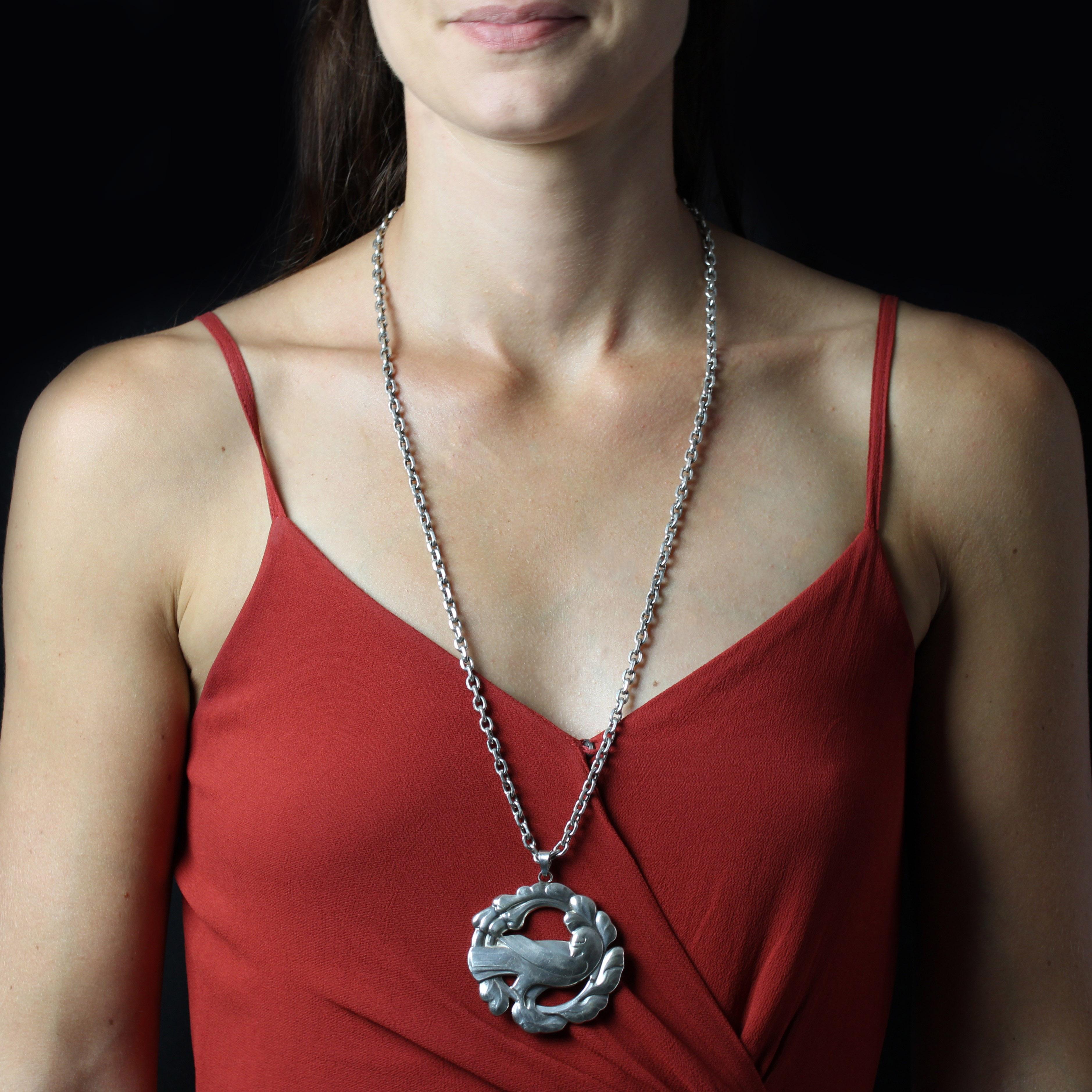 Pendentif et chaîne en argent, poinçon du crabe.
Important pendentif en argent ancien représentant une colombe dans une couronne végétale ajourée. Il est accompagné d'une chaîne en argent. Le fermoir est un anneau à ressort avec une chaîne de