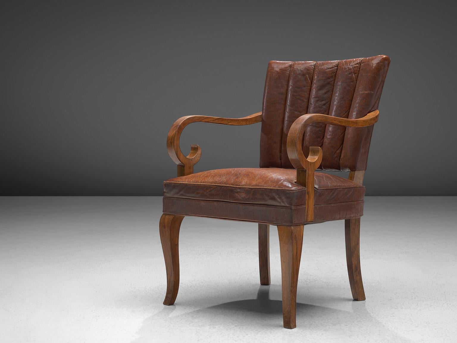Armchair, leather and walnut, Denmark, 1940s.

This dining chair has incredible sensuous details. This is for instance visible in the swirling armrests or the tapered and curved legs. The lines in the chair are very sharp whereas the forms in