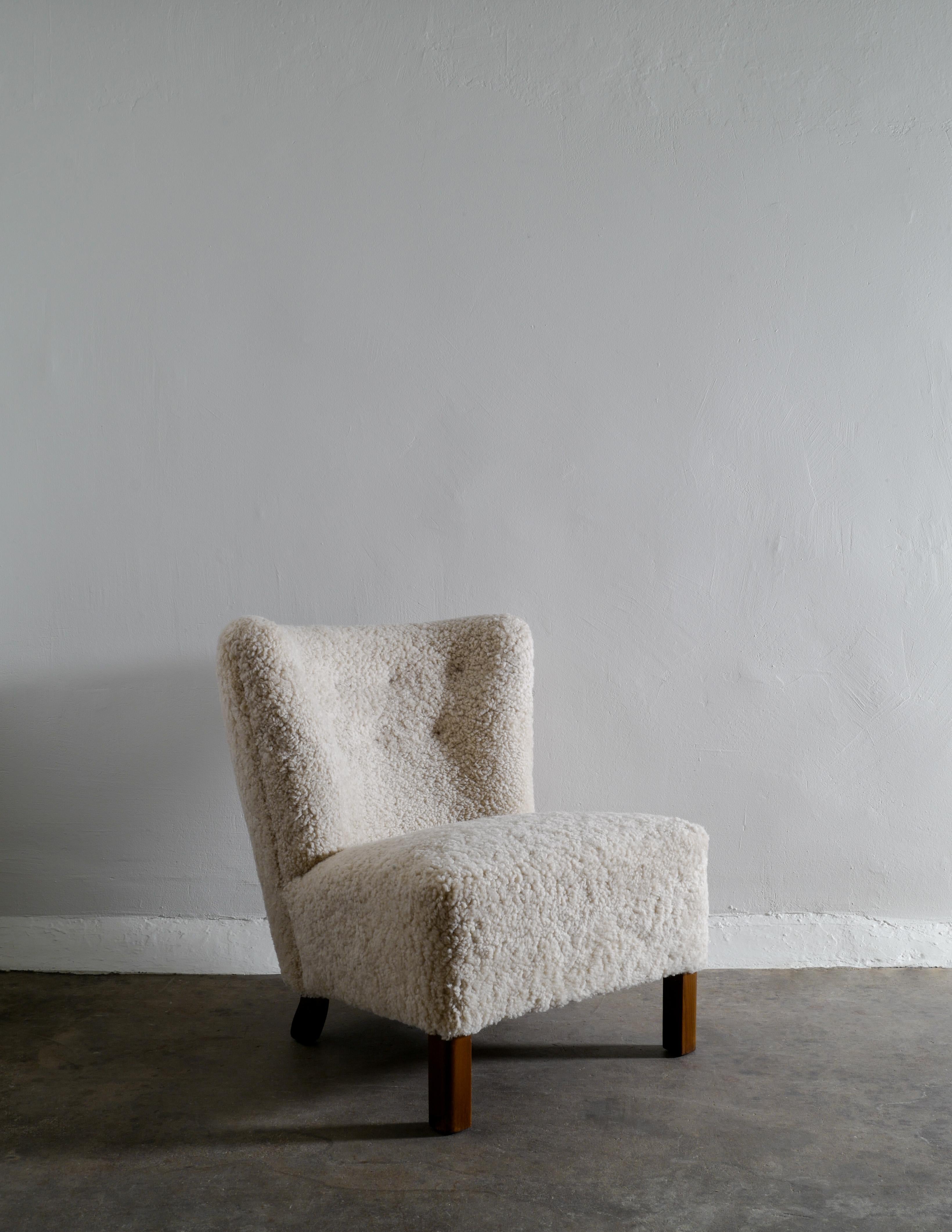 Rare armless easy chair produced in Denmark in the 1940s by unknown designer. Fully restored and upholstered in sheepskin. Dark stained oak feet. Attributed to Gösta Jonsson. 

Dimensions: H: 78 cm W: 62 cm D: 80 cm SH: 43 cm.