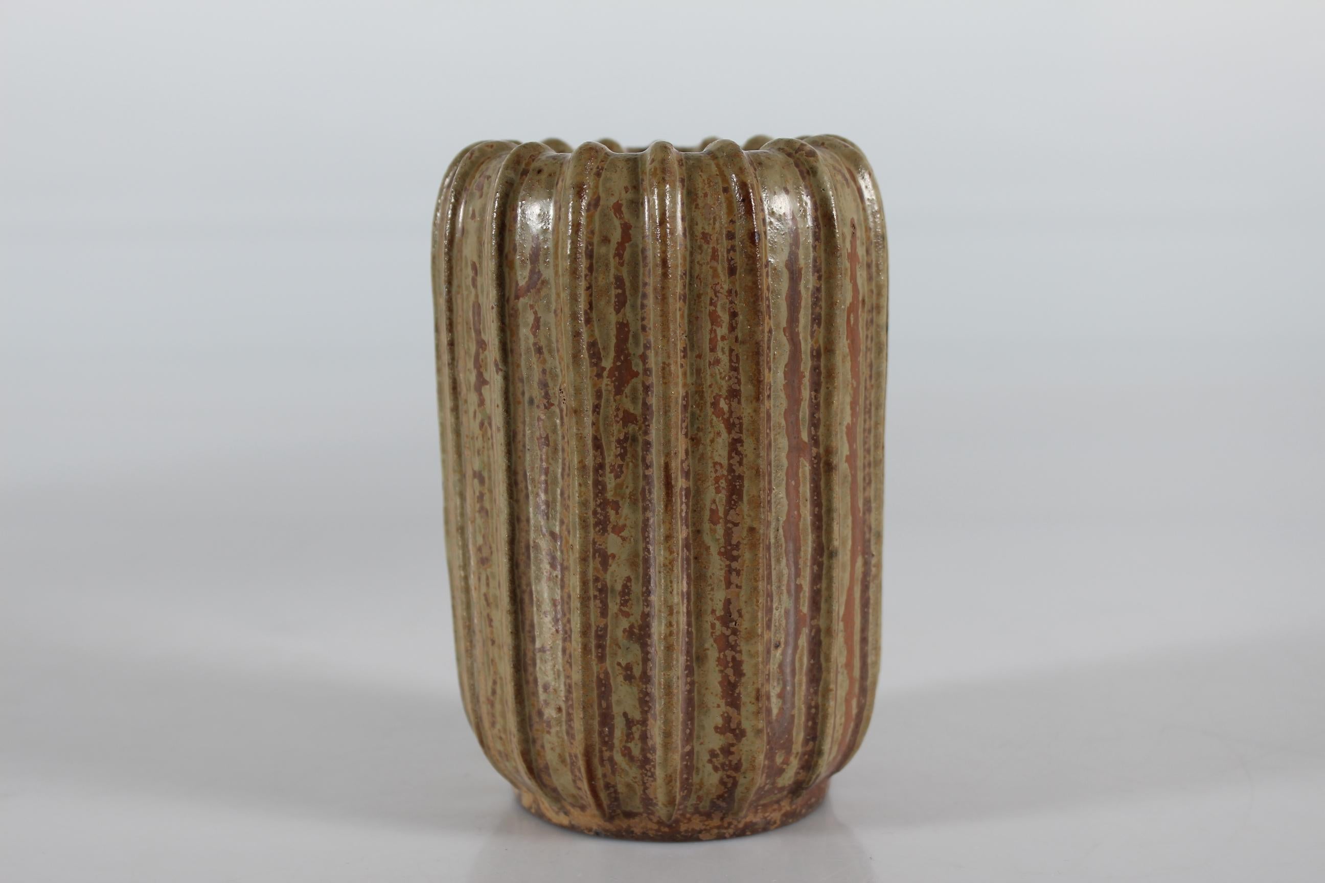 Vase cylindrique cannelé Art Déco du céramiste danois Arne Bang (1901-1983).

Le vase est décoré d'une glaçure mouchetée de couleur brune et terreuse.

Marqué sur le fond d'un monogramme d'Arne Bang et du numéro 37.

Bon état vintage sans
