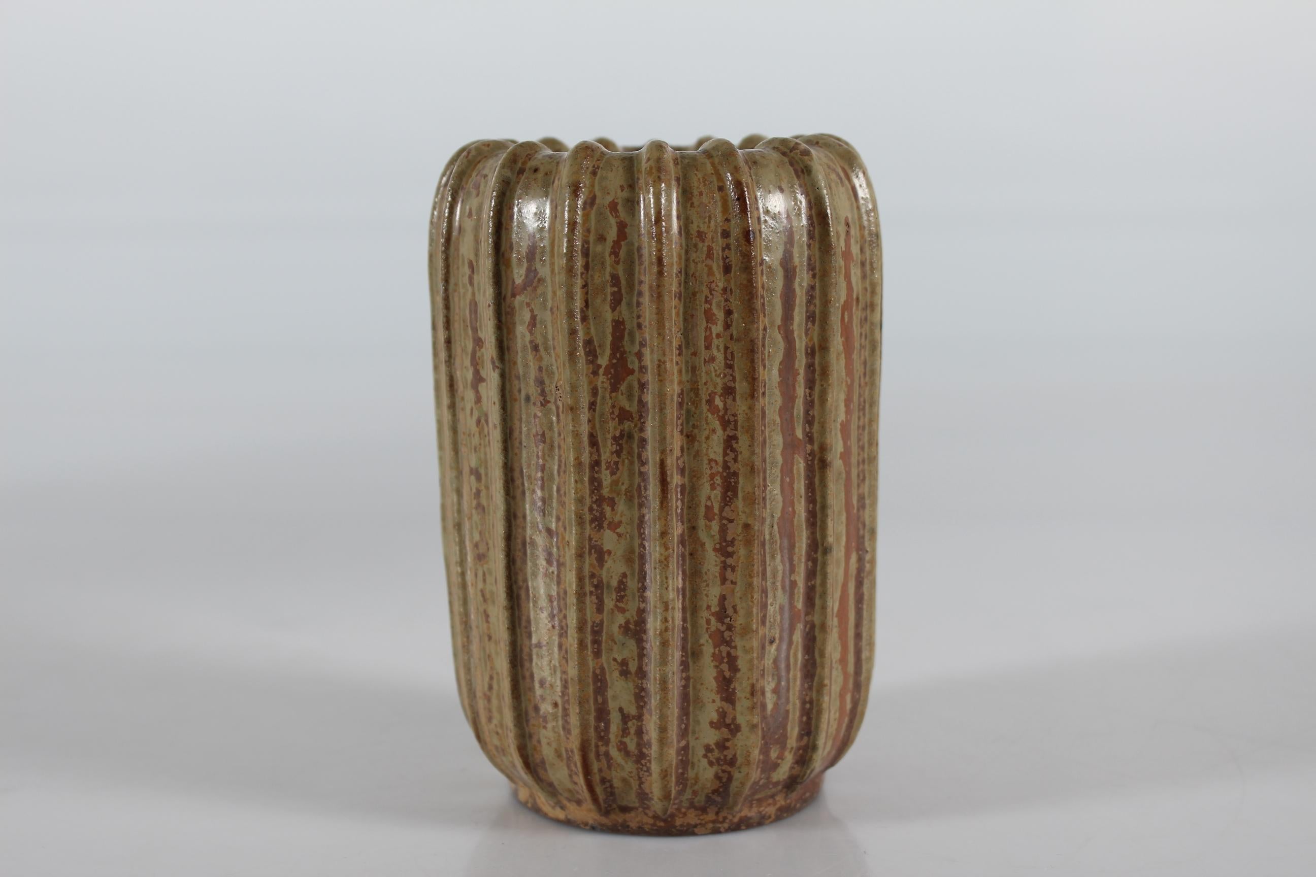 Esbelto jarrón cilíndrico estriado Art Decó del ceramista danés Arne Bang (1901-1983).

El jarrón está decorado con vidriado moteado de color marrón y tierra.

Marcado en la parte inferior con el monograma de Arne Bang y el número 37.

Buen estado