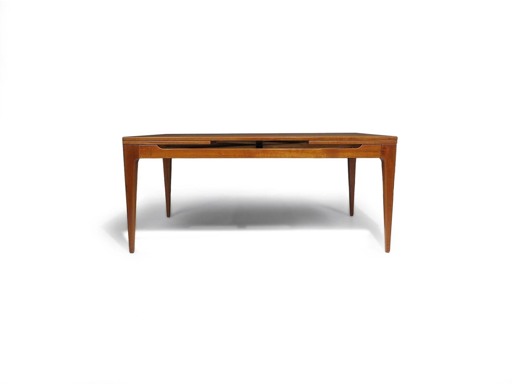 Table de salle à manger du milieu du siècle conçue par Arne Hovmand/Olsen, vers 1955, Danemark. La table se compose d'un cadre sculpté et de pieds effilés en teck assorti au livre. Comprend deux feuilles hollandaises cachées de 21,50