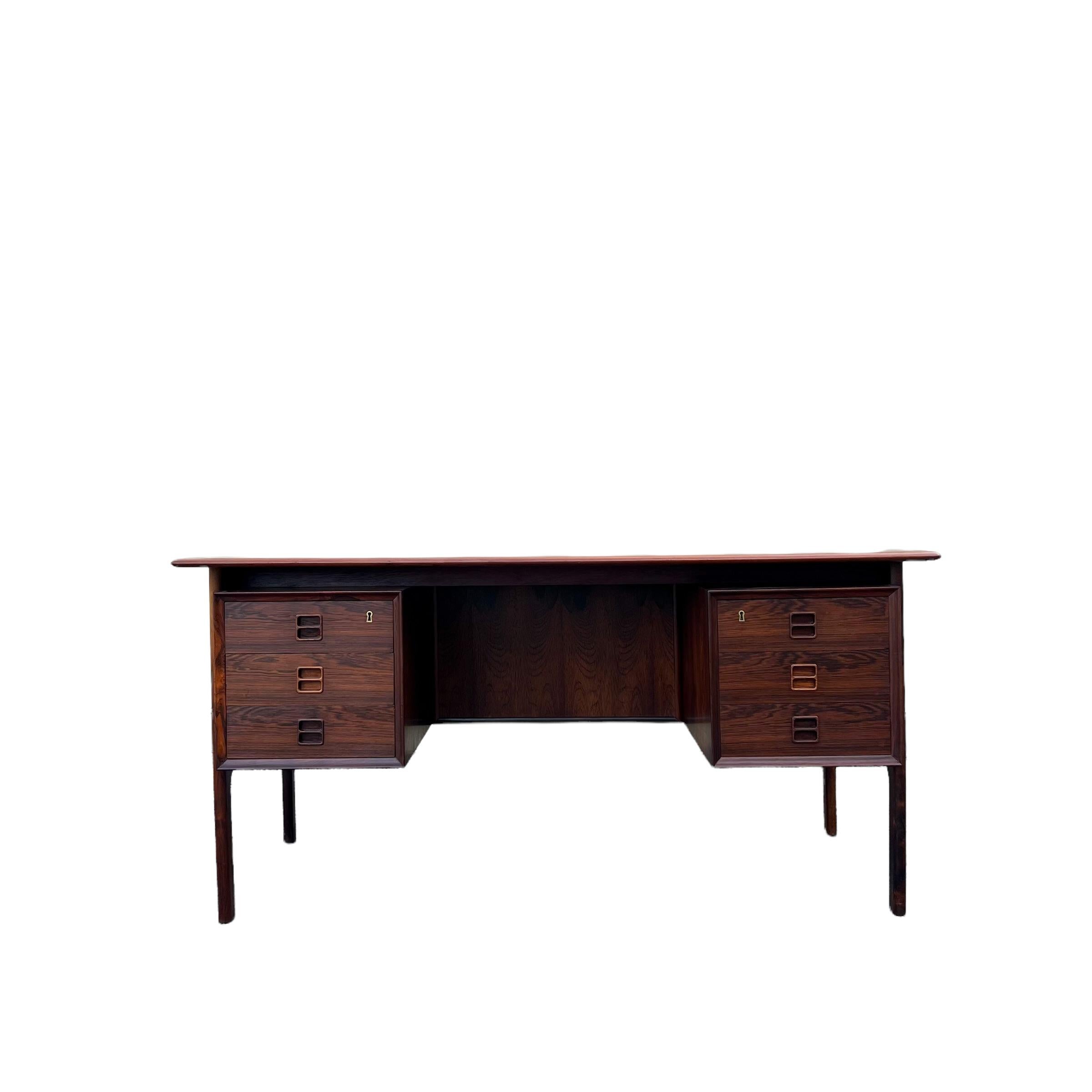 Stunning rosewood executive desk designed by Arne Vodder for Sibast. This desk features and finished back with open shelves for additional storage. The finish is in good condition overall. Some light scuffing/scratching and some areas on the top of