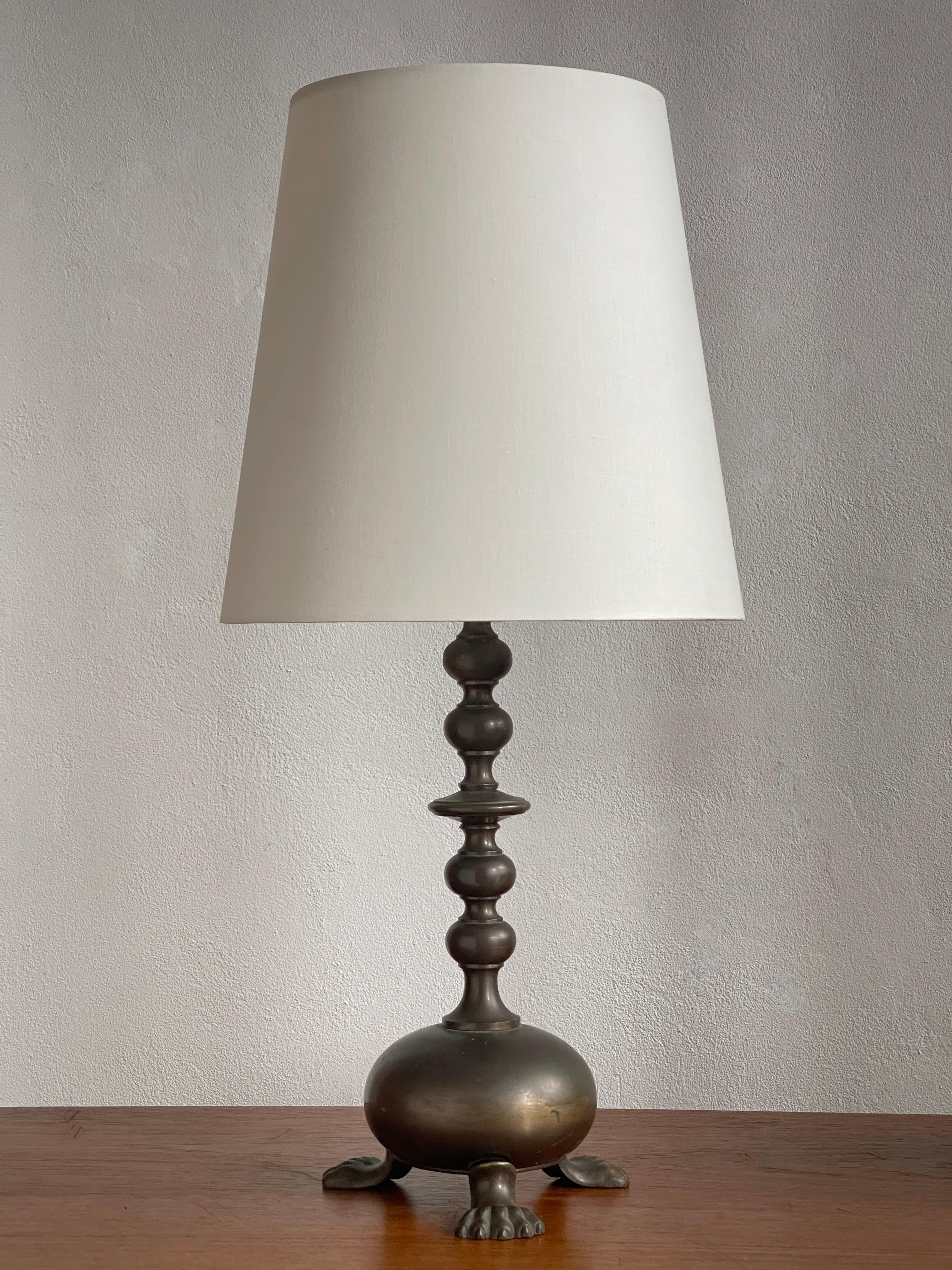 This Danish Art and Craft table lamp from the 1920s is a striking example of the period’s fascination with sculptural forms and artisanal craftsmanship. Crafted in patinated bronze, the lamp embodies the meticulous attention to detail and the
