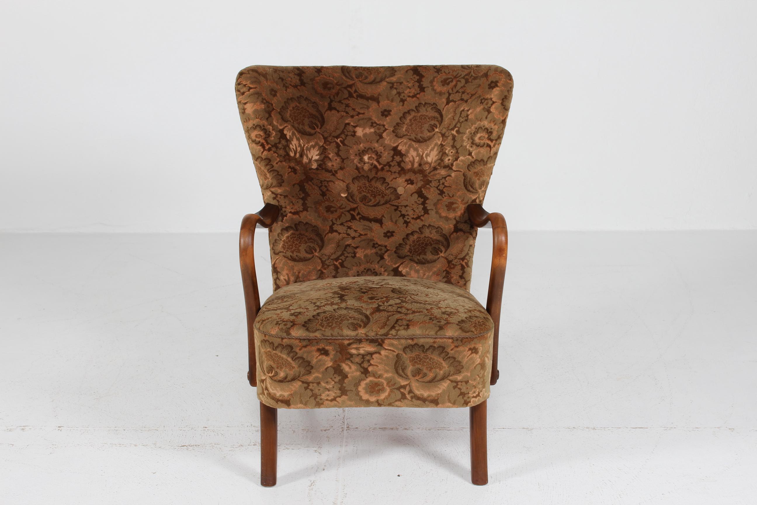 Comoda poltrona danese Art Deco degli anni '40 completamente rivestita di velluto a motivi floreali. Gambe e braccioli in faggio tinto.

Realizzato a mano negli anni '40 dalla Slagelse Stolefabrik/møbelfabrik

La sedia è in buone e robuste
