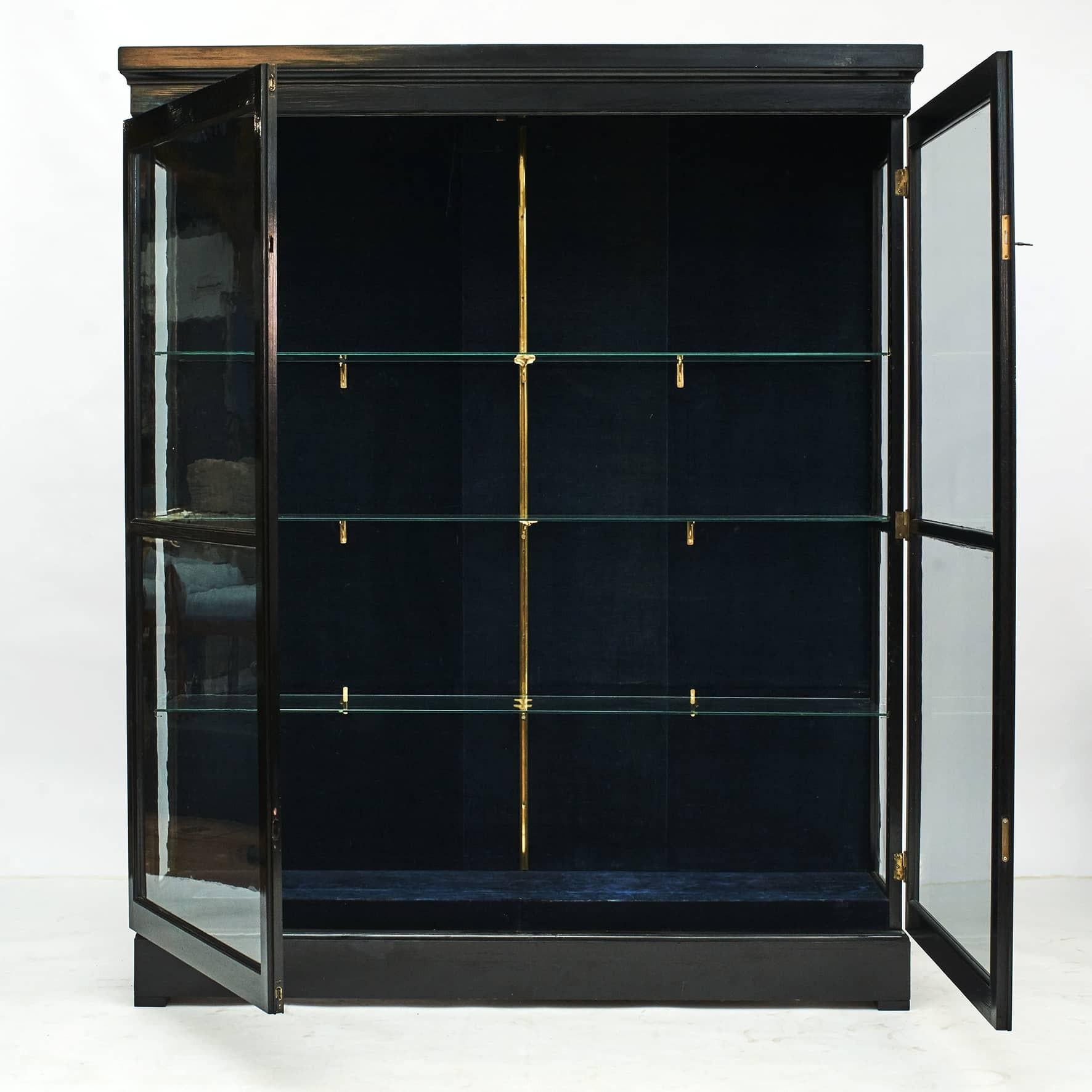 Danish Art Deco two-door vitrine cabinet in black polished pine. Former museum showcase.
Three-sided glazed body, interior with four glass shelves on brass brackets. Doors with two locks, one on the top and a bottom.
Denmark 1920-1925.
 