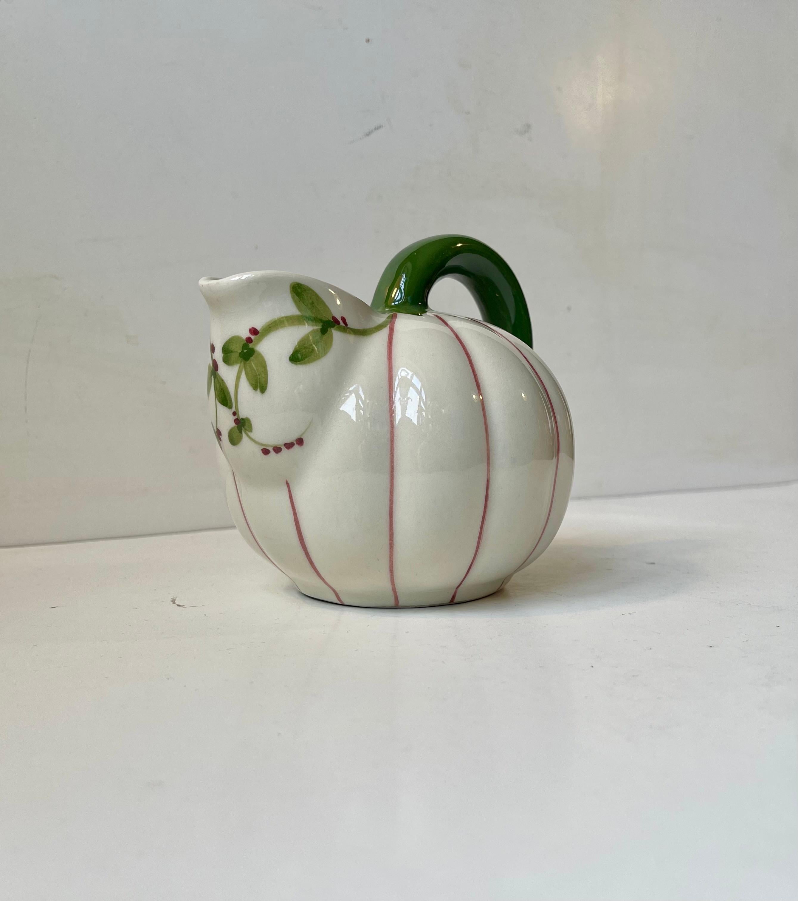 Piccola brocca o vaso con manico in ceramica smaltata in stile art déco. Decorato con strisce rosa e dettagli floreali. Condizioni d'epoca belle e ben tenute. Marchio del produttore alla base. 

Misure: H: 14/10 cm, Diametro: 12 cm.