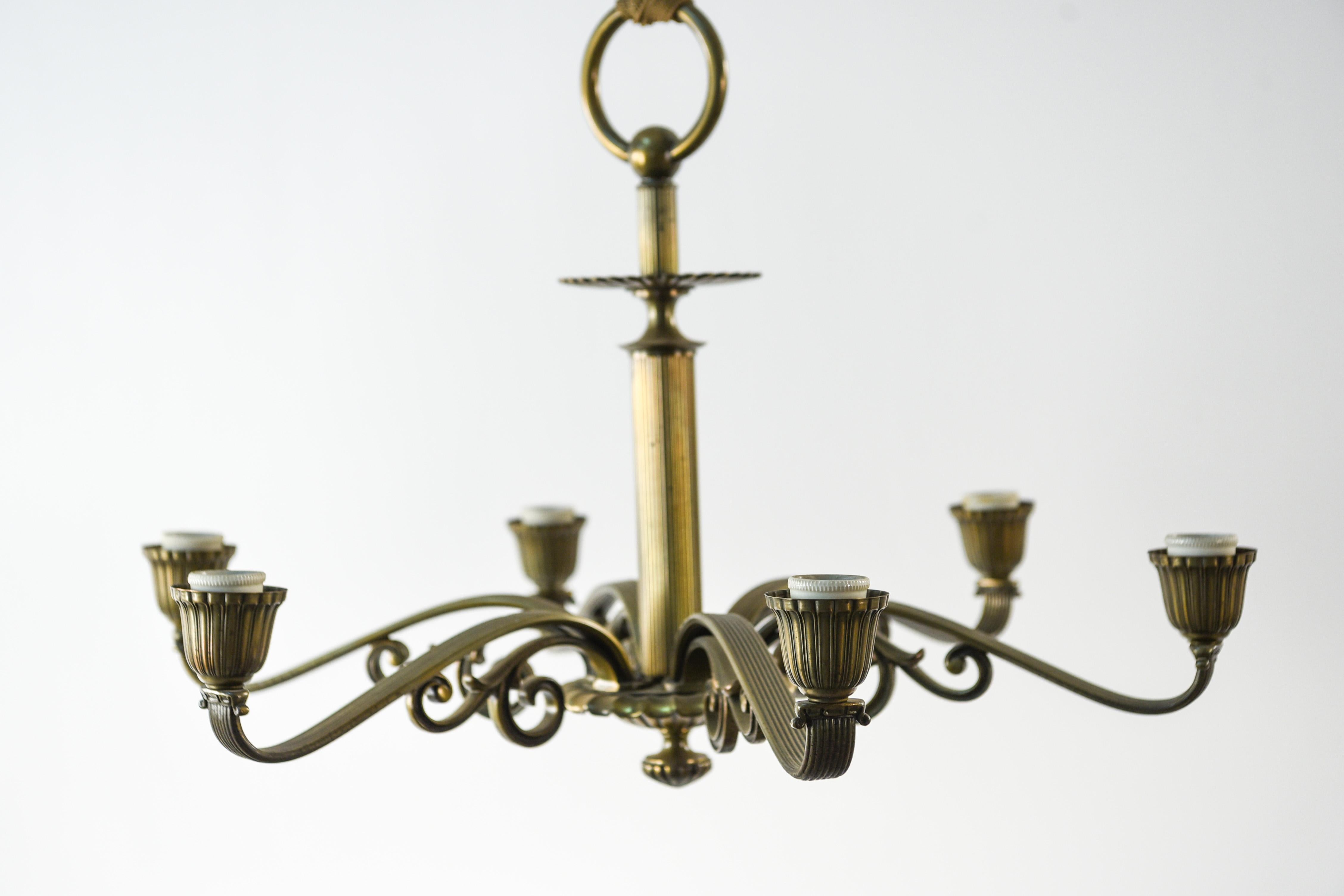This six-arm Danish chandelier is from the Art Deco period. This piece features a reeded body and arms, with ornate swirls below. This chandelier has a timeless elegance to it.