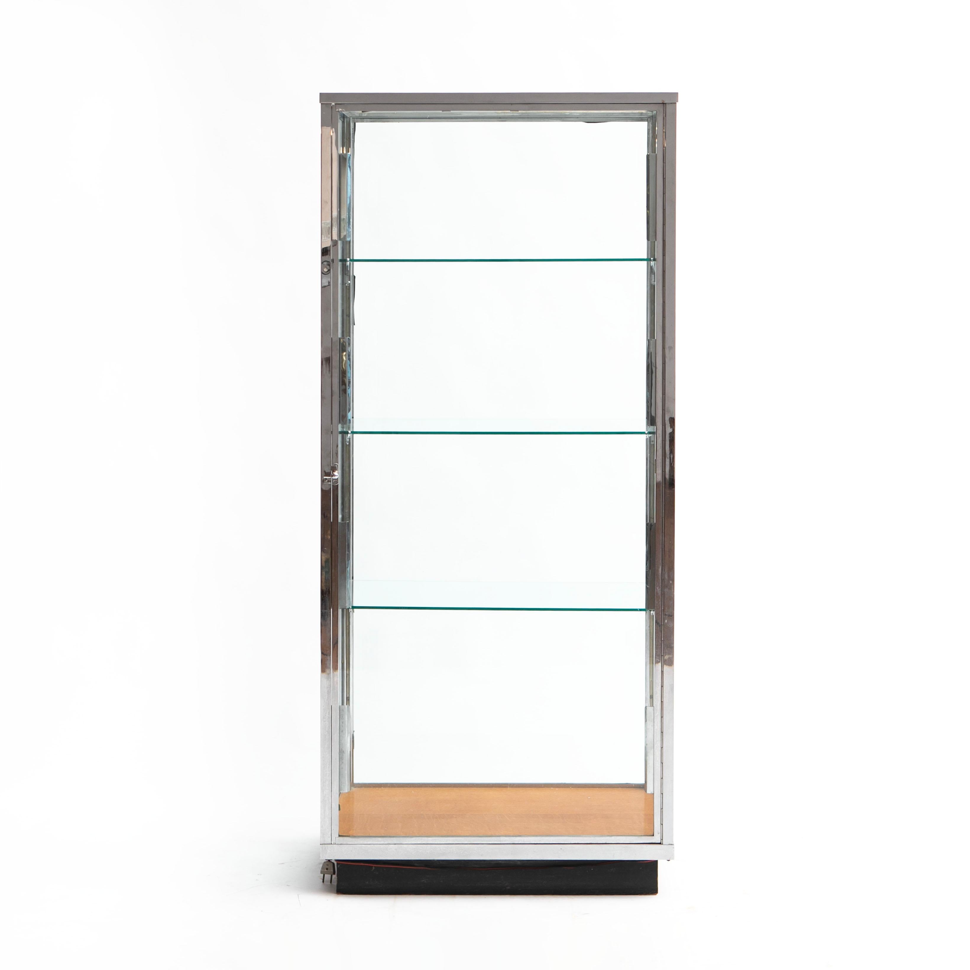 A large Danish art deco glass and chromed brass lighted display / storage cabinet.
Freestanding with glass on all four sides. Four glass shelves and a wooden 