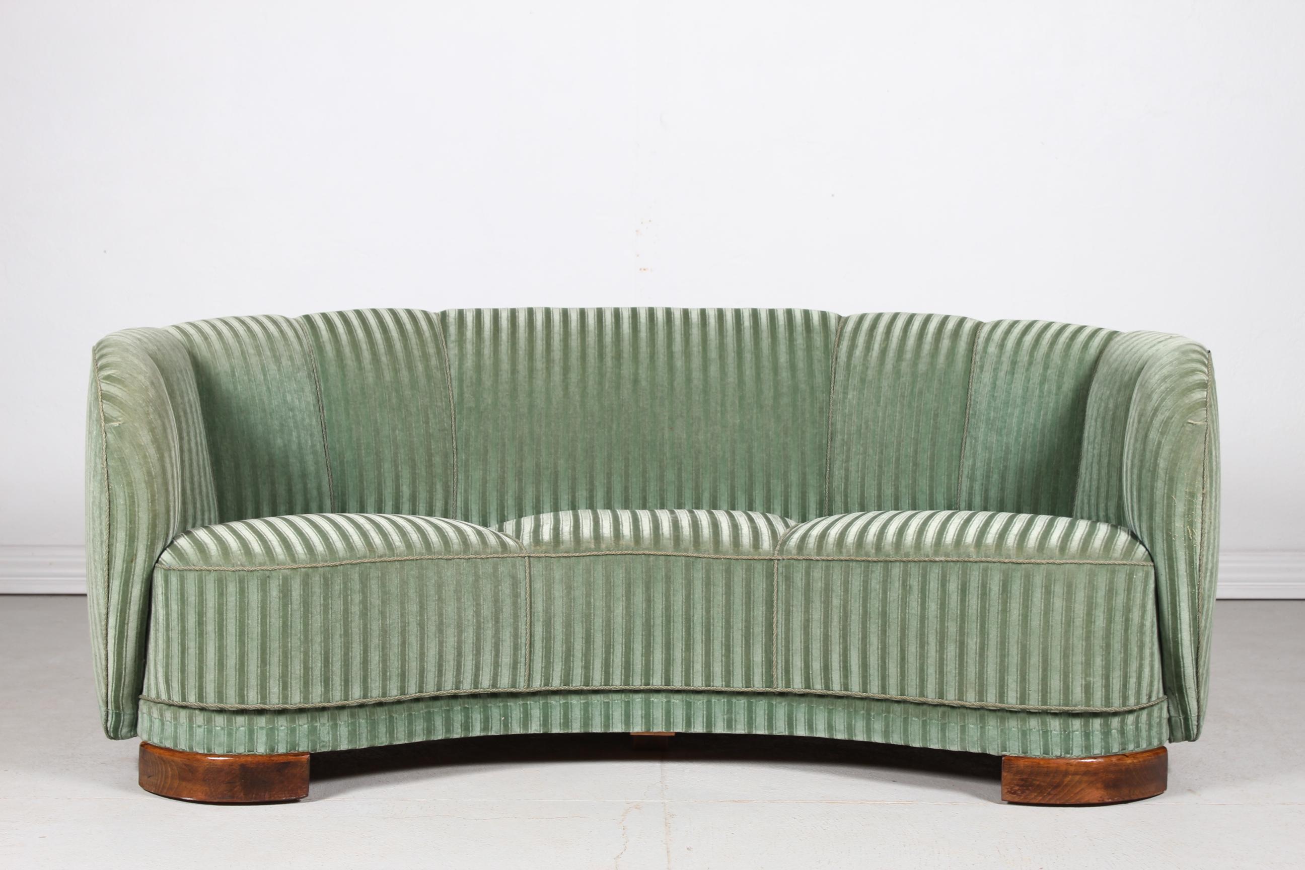 Danish curved, banana shaped Art Deco couch or sofa made in the 1940s.
The legs are made of dark stained wood and the sofa is upholstered with green striped velour.
Made by Danish furniture maker in the 1940s. 

The couch is in good vintage